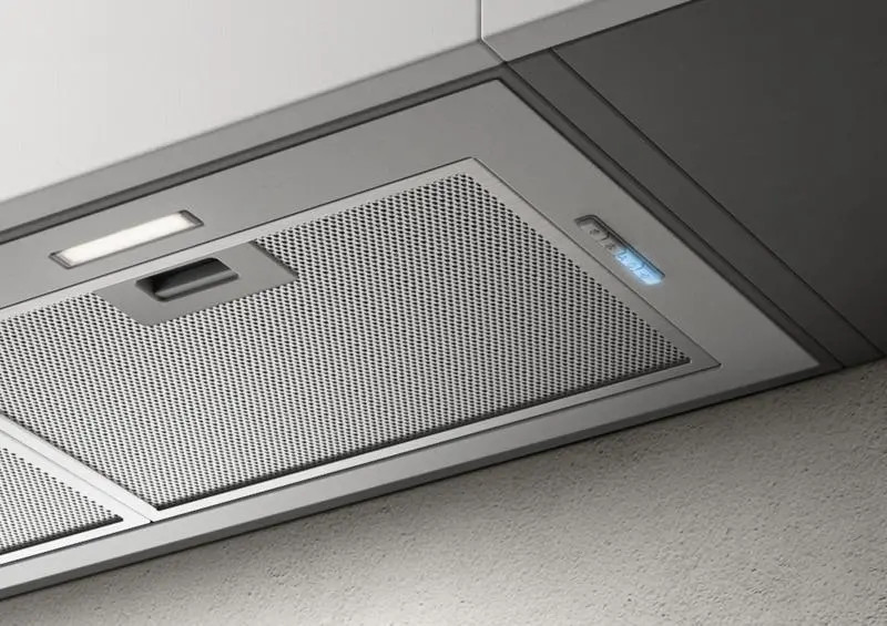 Zbliżenie okapu ze stali nierdzewnej, ze światłami i panelem sterowania.