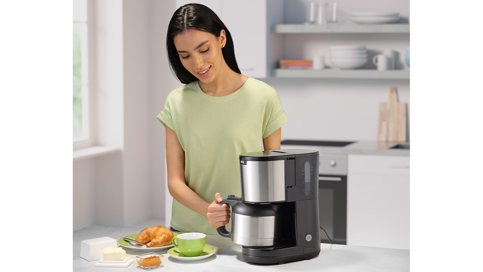 Eine Frau, die Kaffee zubereitet, mit Kaffeemaschine, Tasse, Teller mit Essen und Küchenhintergrund.