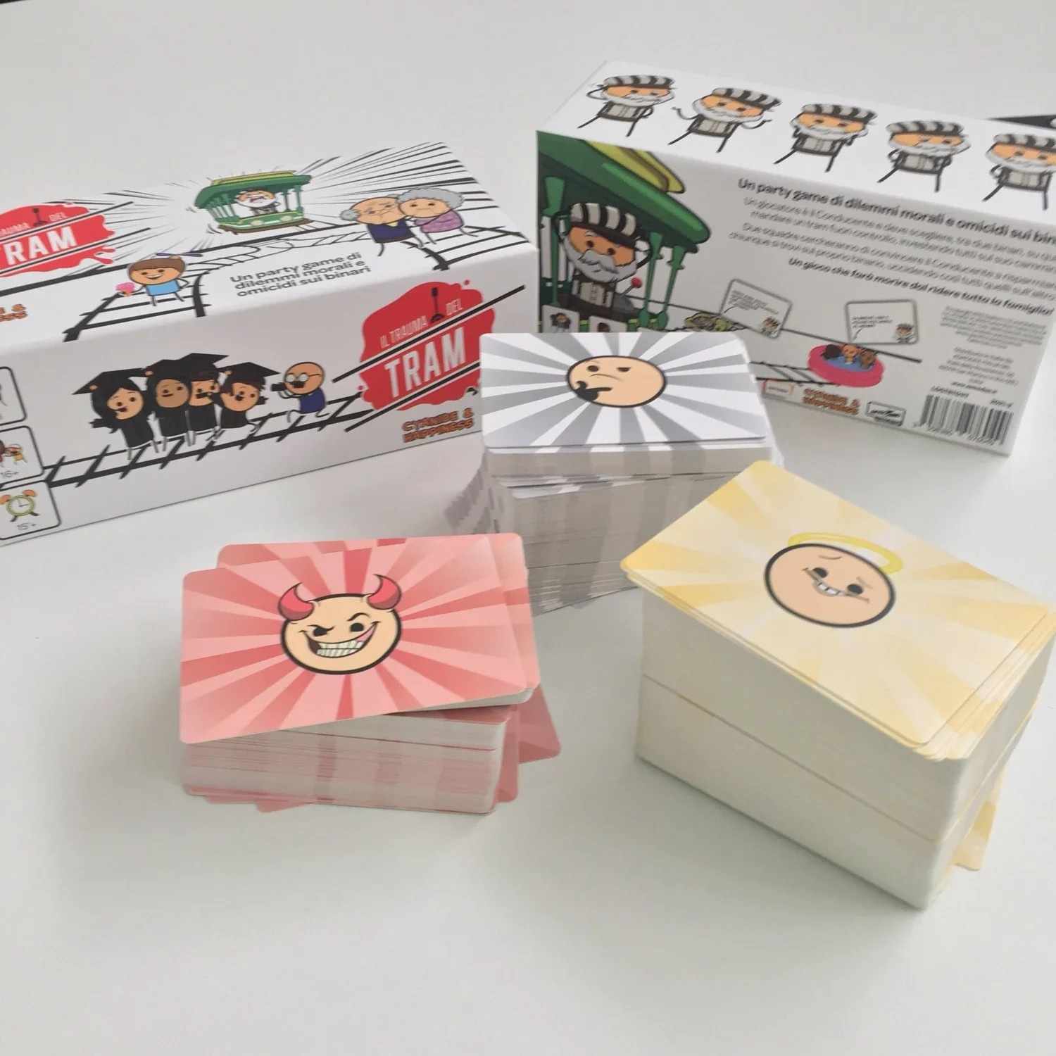 Scatole di gioco e carte con facce di cartoni animati su una superficie bianca. Le scatole hanno illustrazioni e testo.