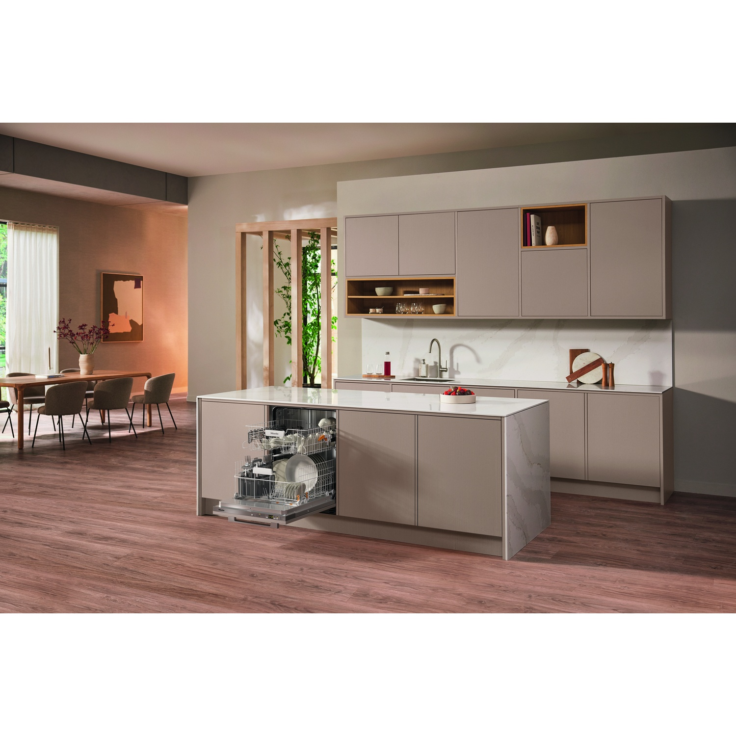 Scena di cucina con lavastoviglie Miele aperta, isola cucina e zona pranzo.