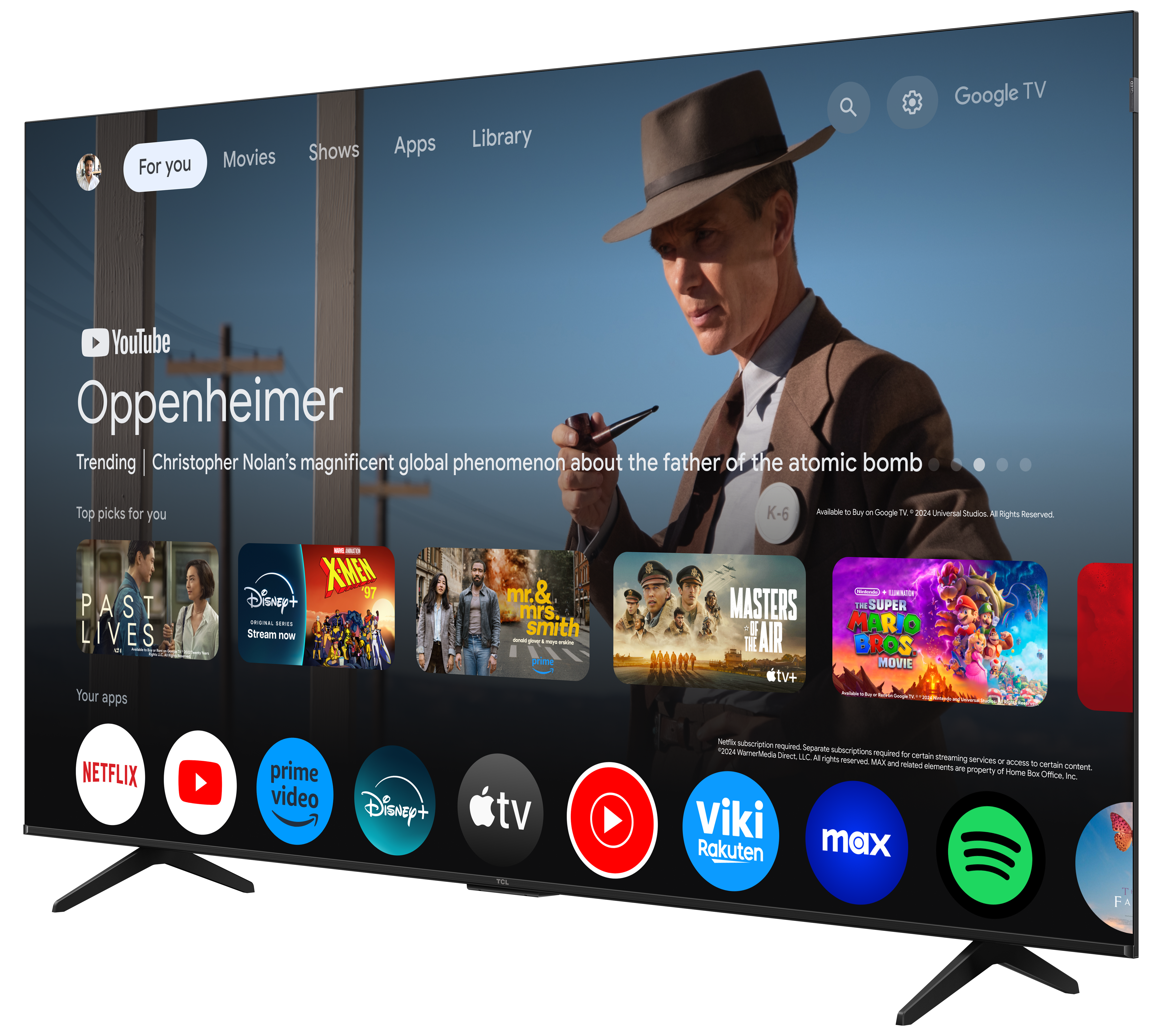 Duży telewizor wyświetla interfejs Google TV. Mężczyzna w kapeluszu po prawej stronie. Poniżej wyświetlane są aplikacje i filmy.