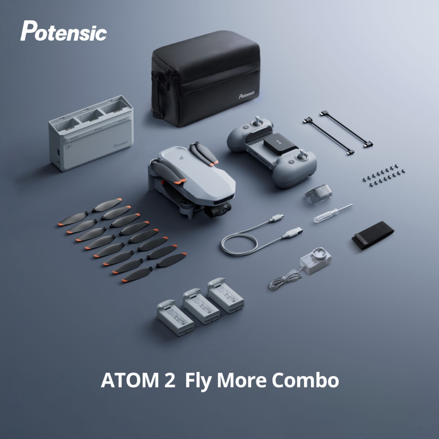 Drone kit with drone, remote, batteries, charger, and accessories on a grey surface.
