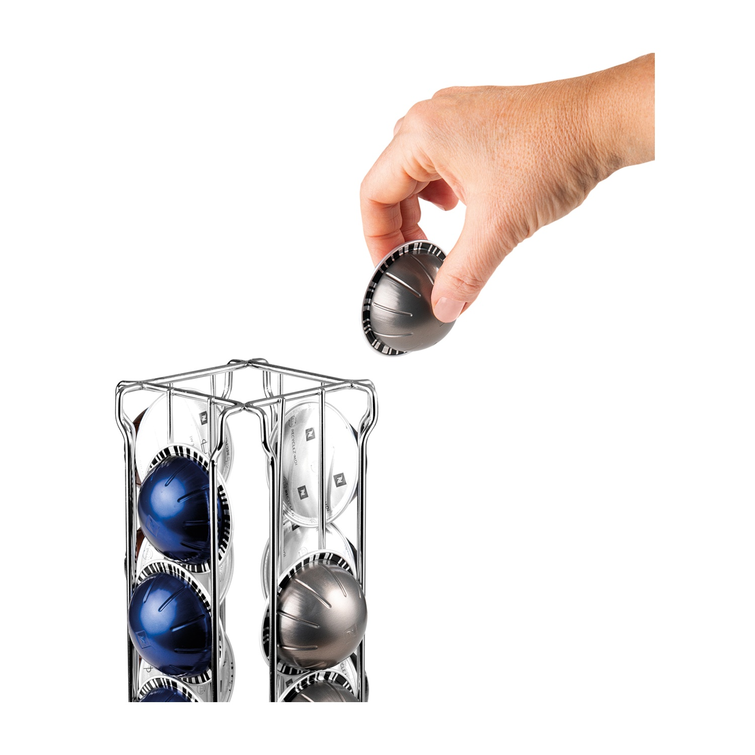 Porta capsule per caffè argentato con capsule blu e grigie. Una mano prende una capsula.