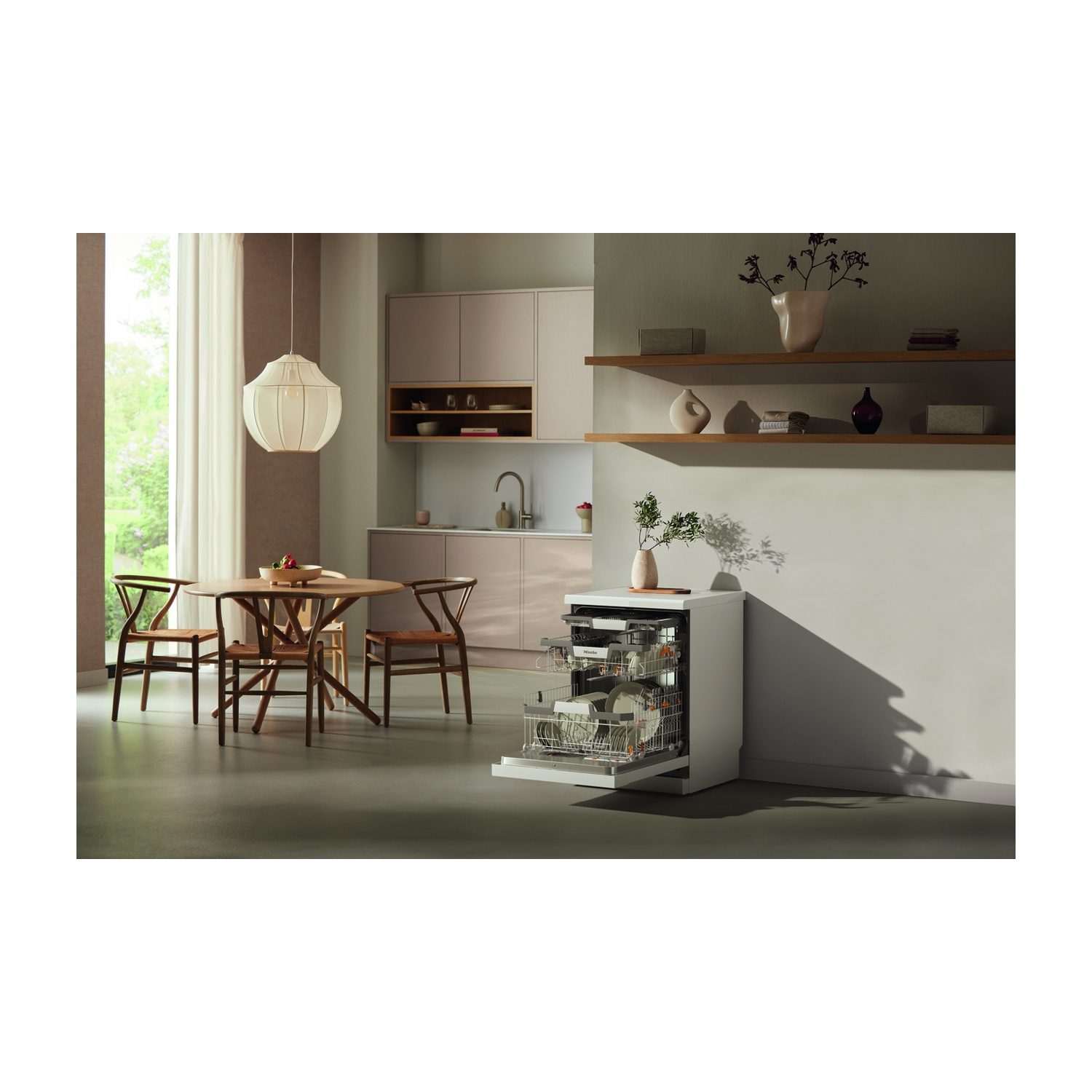 Scena cucina con lavastoviglie aperta. Tavolo rotondo in legno e sedie. Interior design.