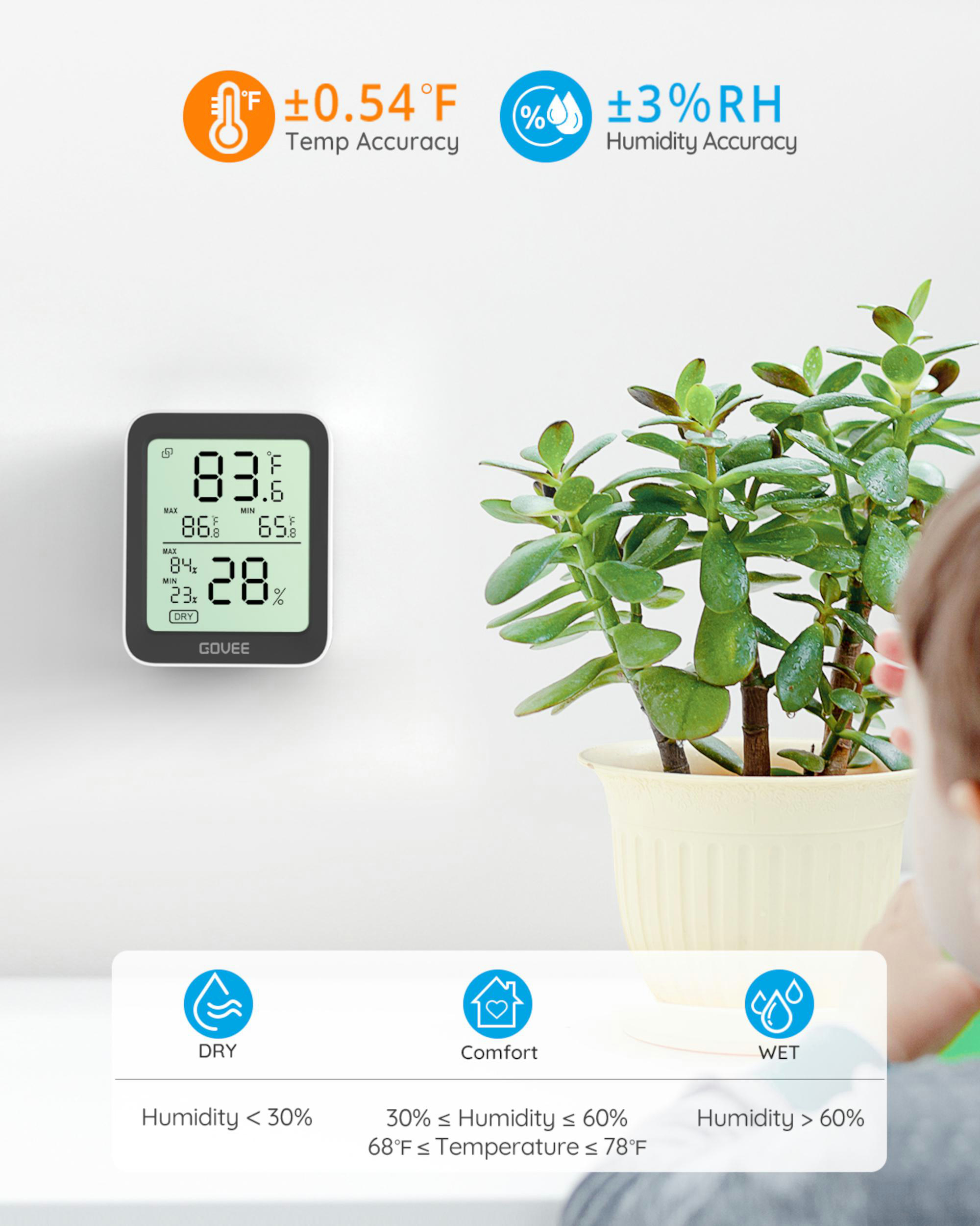 Ein digitales Thermometer, das Temperatur und Luftfeuchtigkeit anzeigt, neben einer Topfpflanze.
