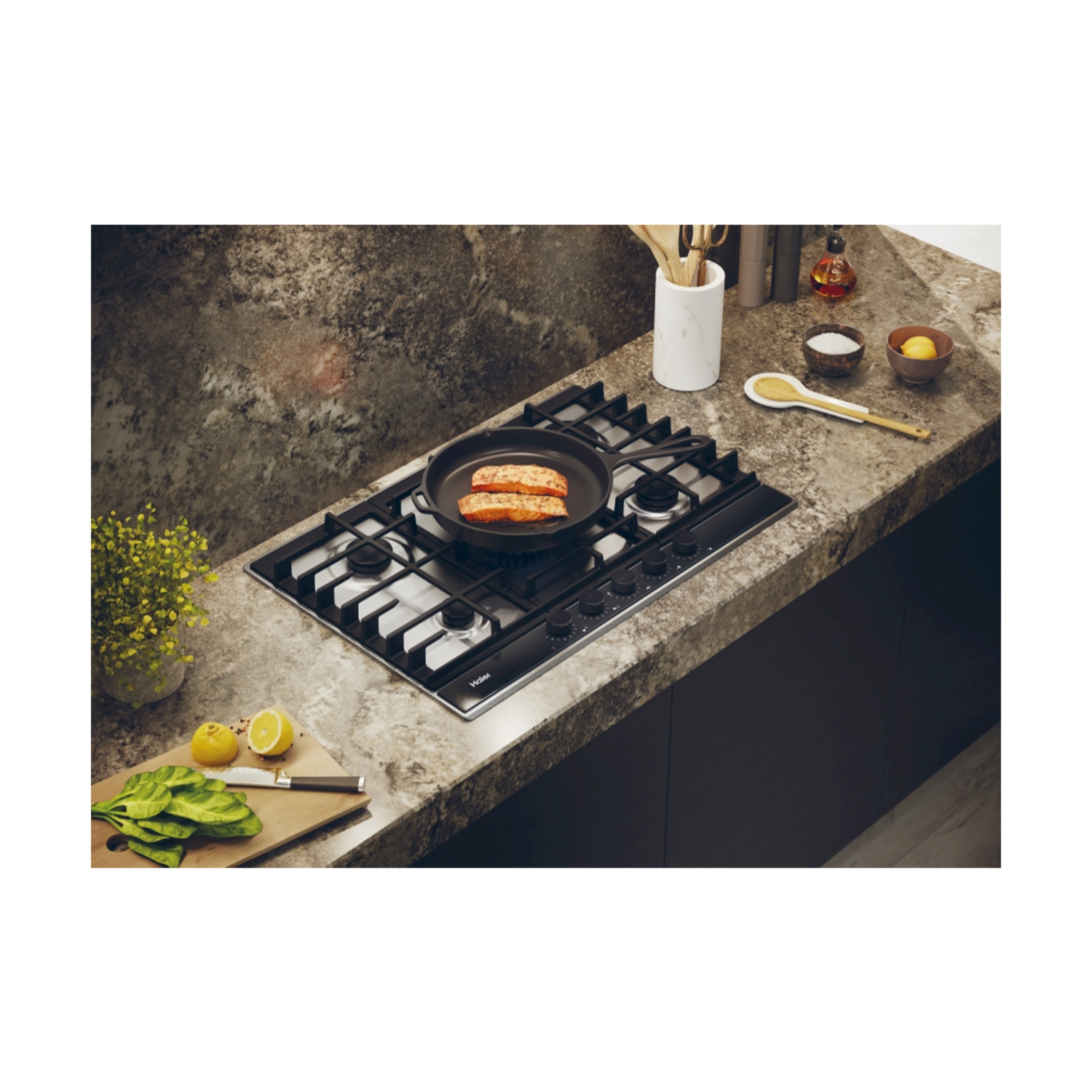 Piano cottura a gas con una padella con cibo, circondata da utensili, limoni e spinaci.