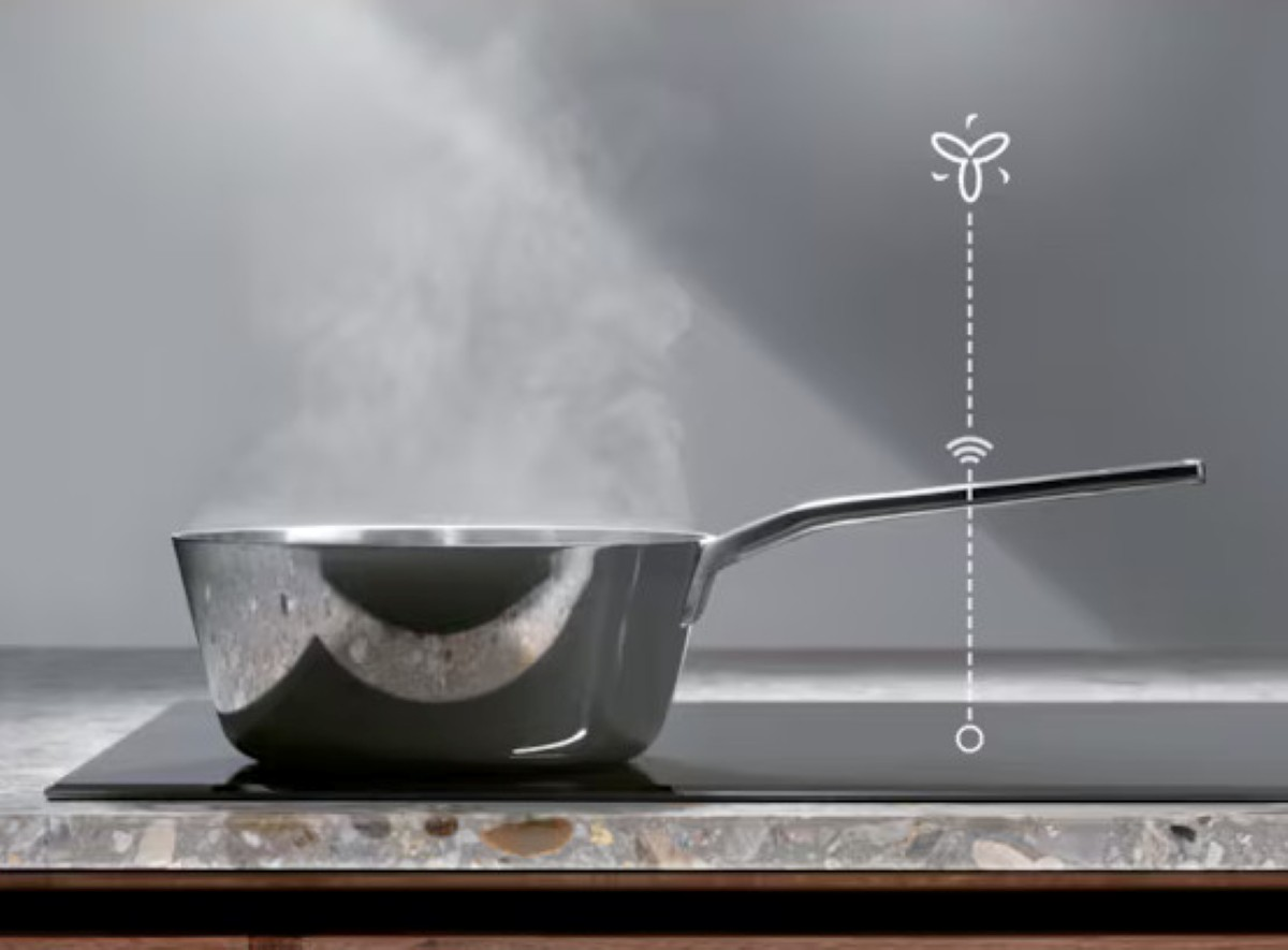 Garnek ze stali nierdzewnej z parą nad nim na czarnej płycie grzejnej, z ikoną wentylatora.