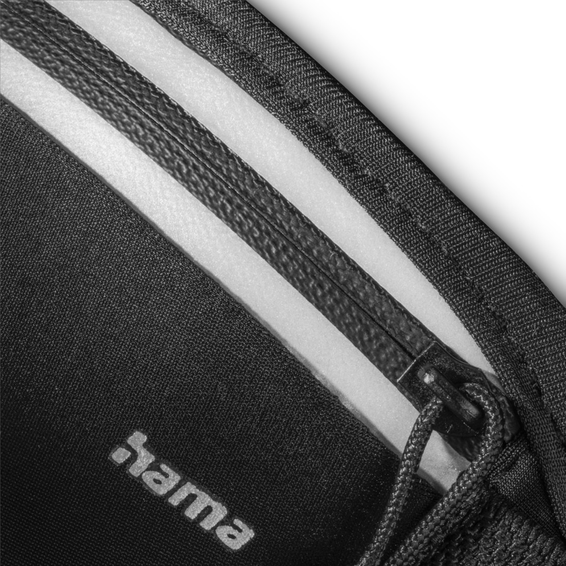 Schwarze Ecke einer Tasche mit weißen Streifen und Reißverschluss. Hama-Logo sichtbar.