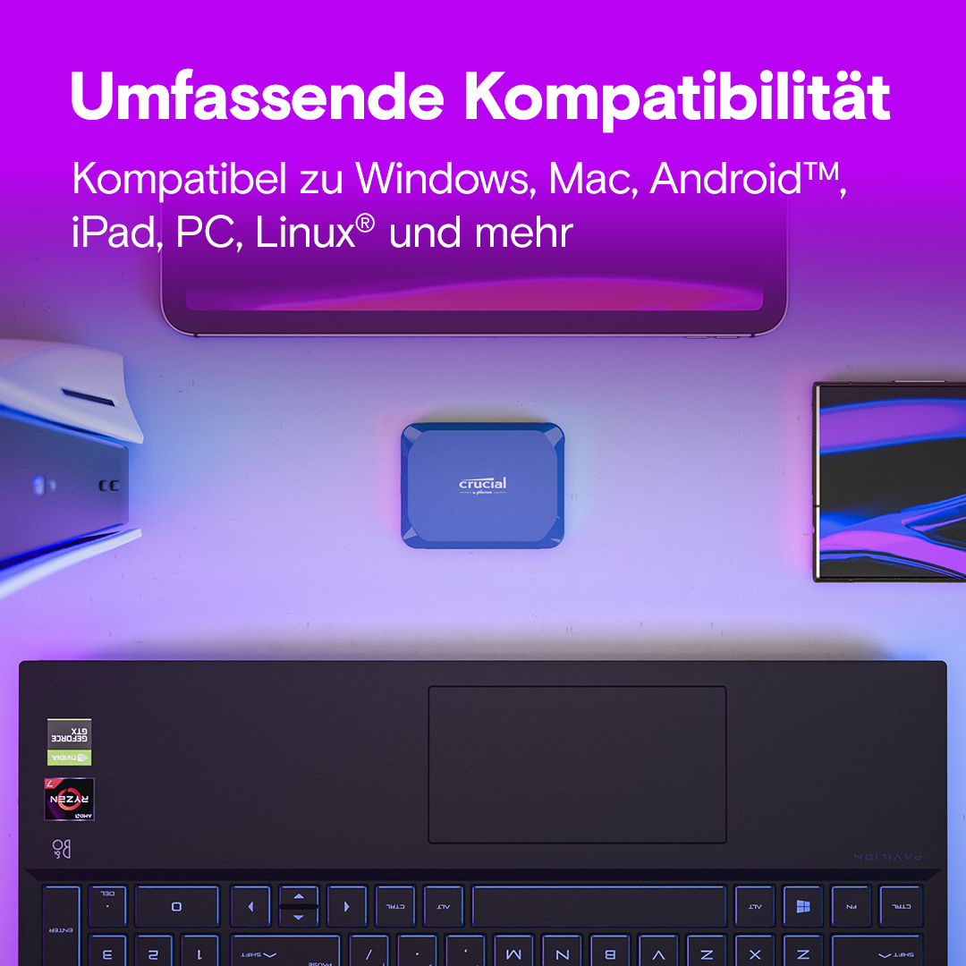 Blaue Crucial SSD auf einem Schreibtisch mit Laptop, Tablet und Monitor. Lila Hintergrund.