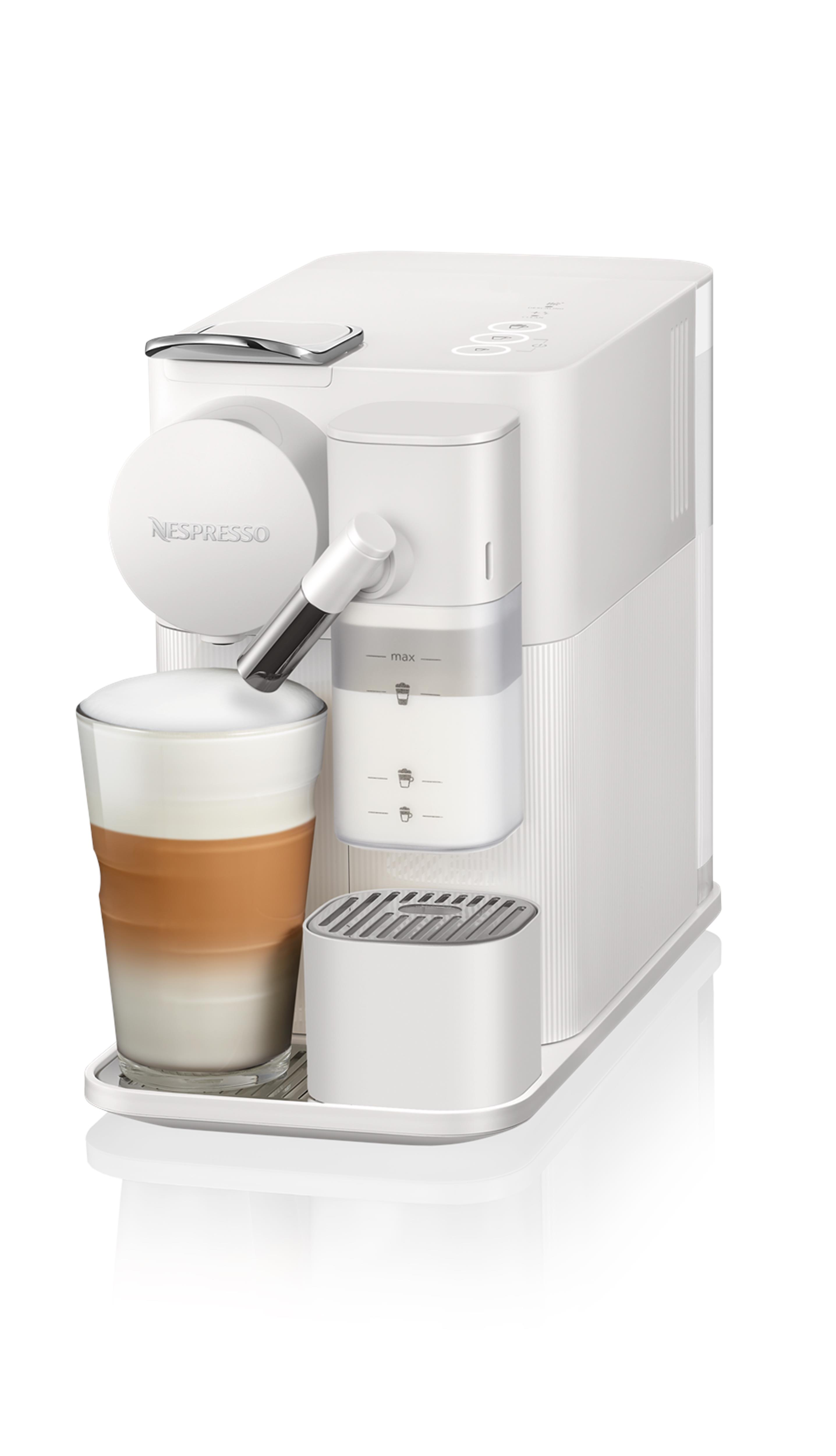 Beyaz kahve makinesi latte yapıyor, katmanlı kahve dolu bir bardak ile.