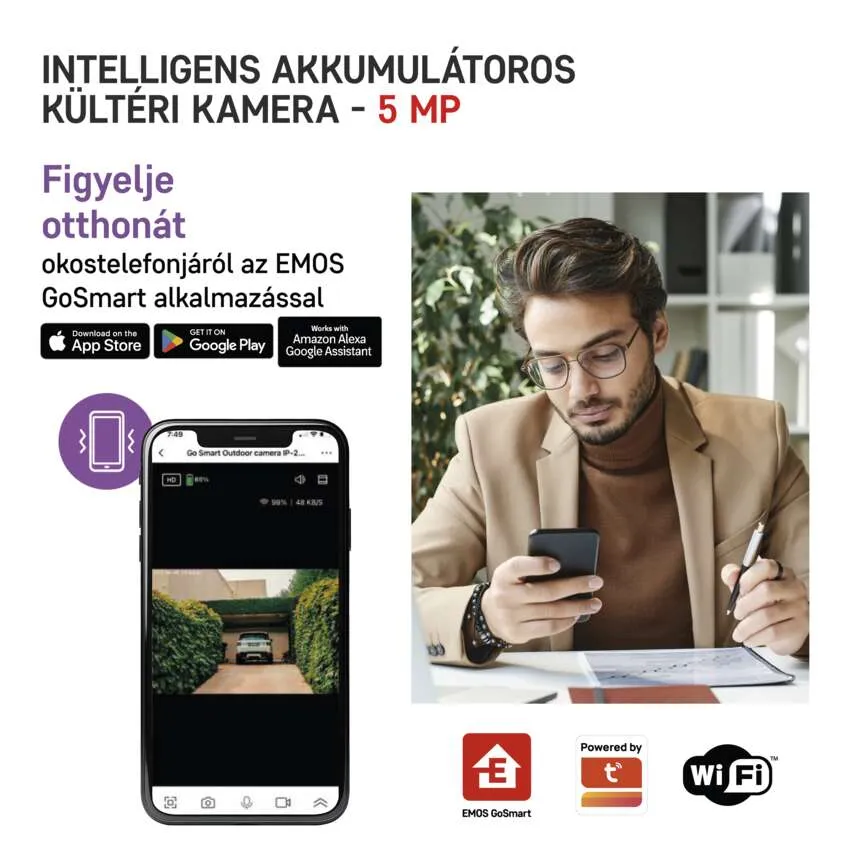 Férfi egy telefont néz, amelyen egy autó kameranézete látható a felhajtón.