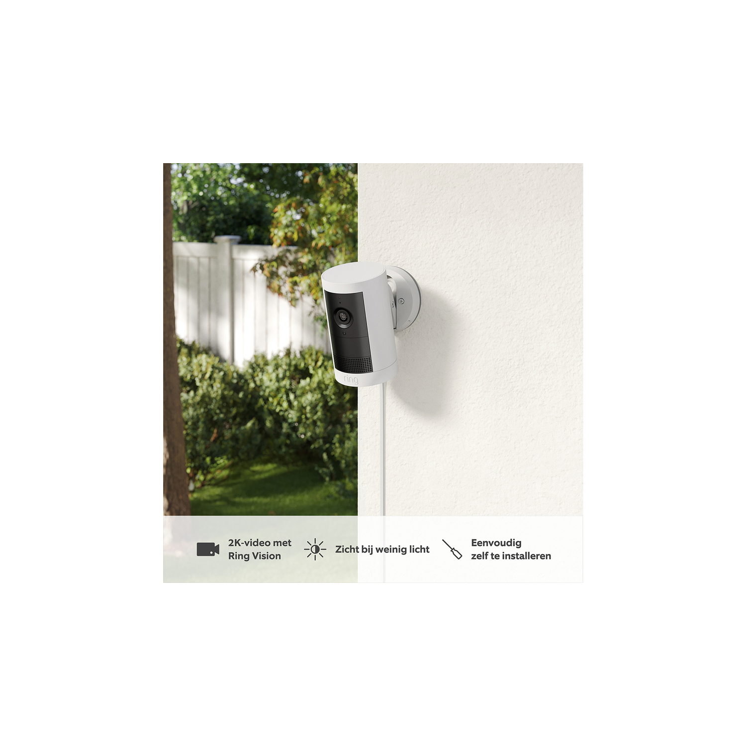 White security camera on wall. Green trees in the background.