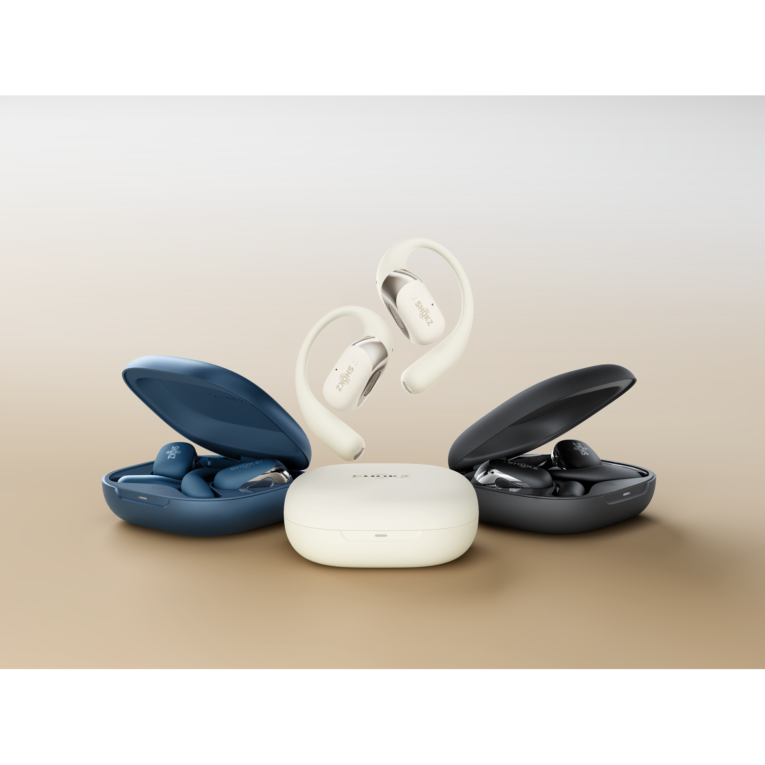 Earbuds, cases in navy, black, and cream. Cream earbuds are suspended above a cream case on a beige surface.