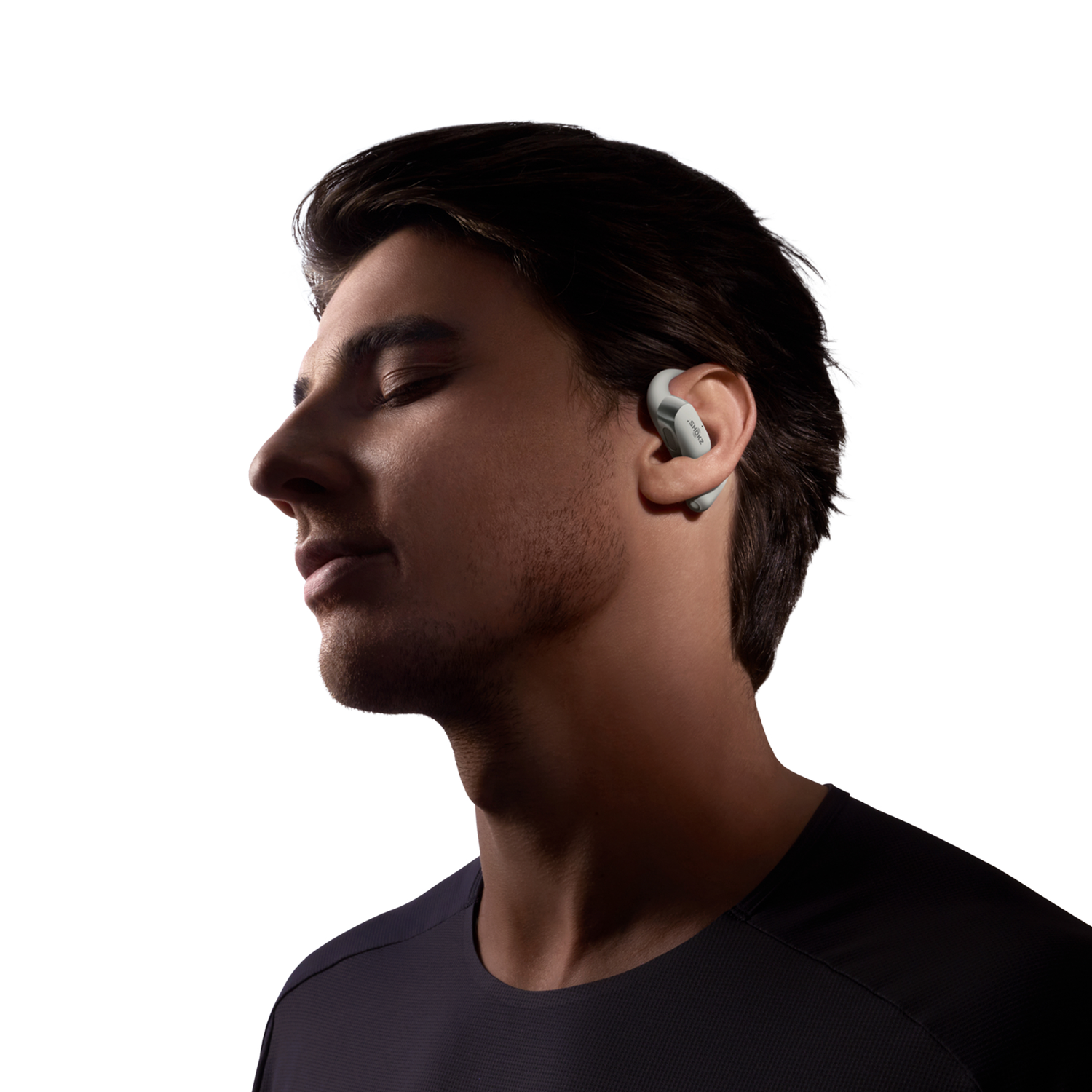 Man with grey earbuds, eyes closed. Background: white.