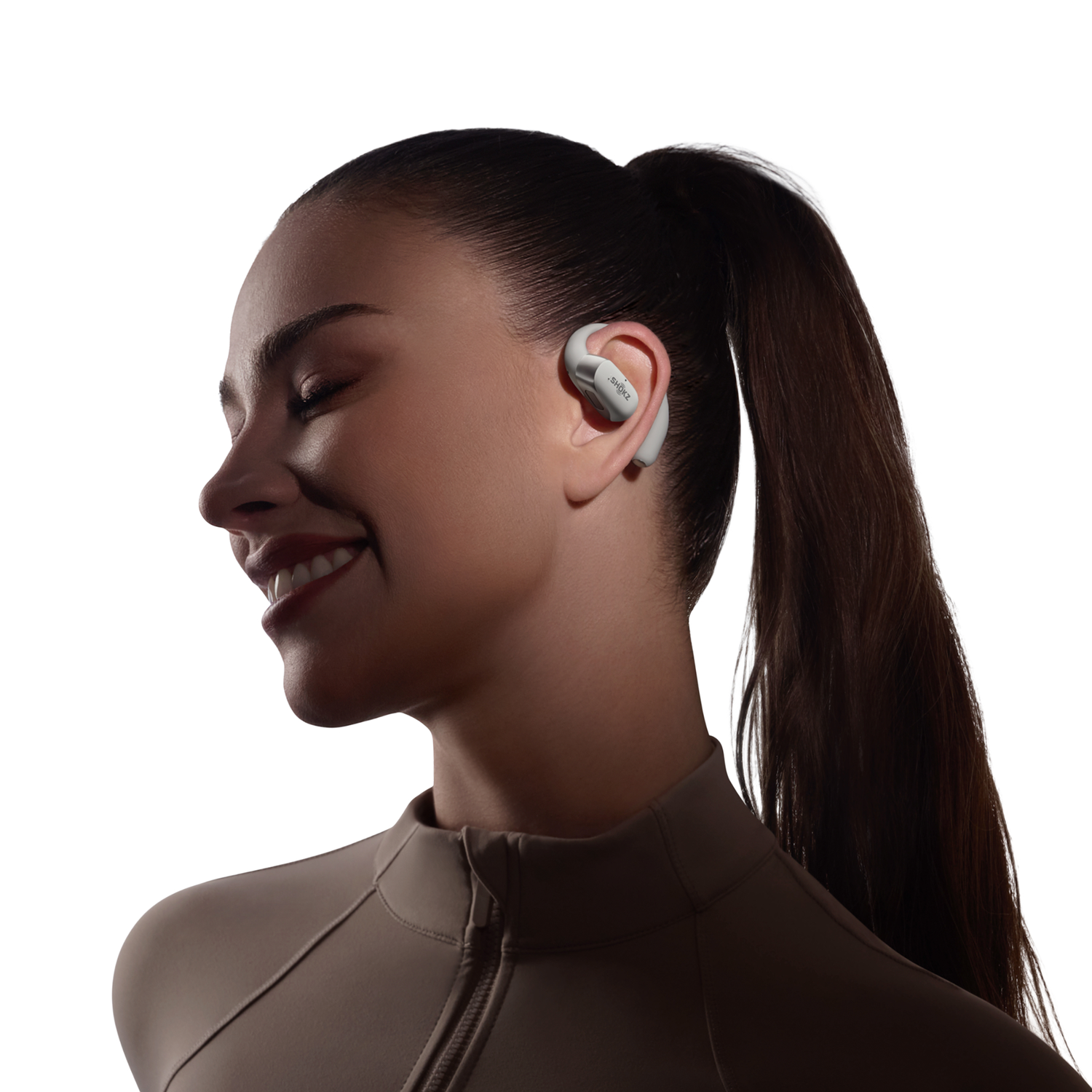 Woman wearing earbuds, smiling. Background: white.
