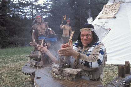 Männer in indianischer Kleidung um ein Feuer. Einer zündet eine Fackel an, andere klatschen.