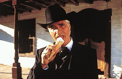 Mann in schwarzem Hut isst Eiswaffel. Western-Saloon im Hintergrund.