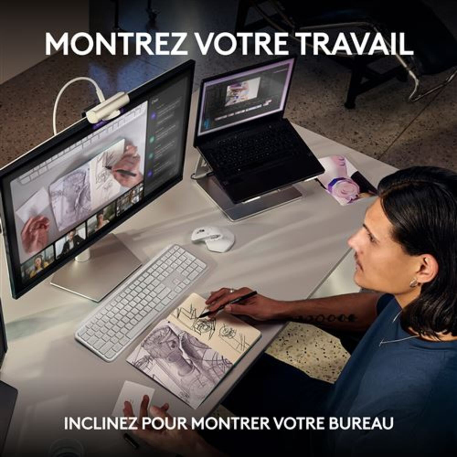 Une personne dessine sur papier à côté d'un ordinateur portable et d'un moniteur. Une webcam est montée sur le moniteur.