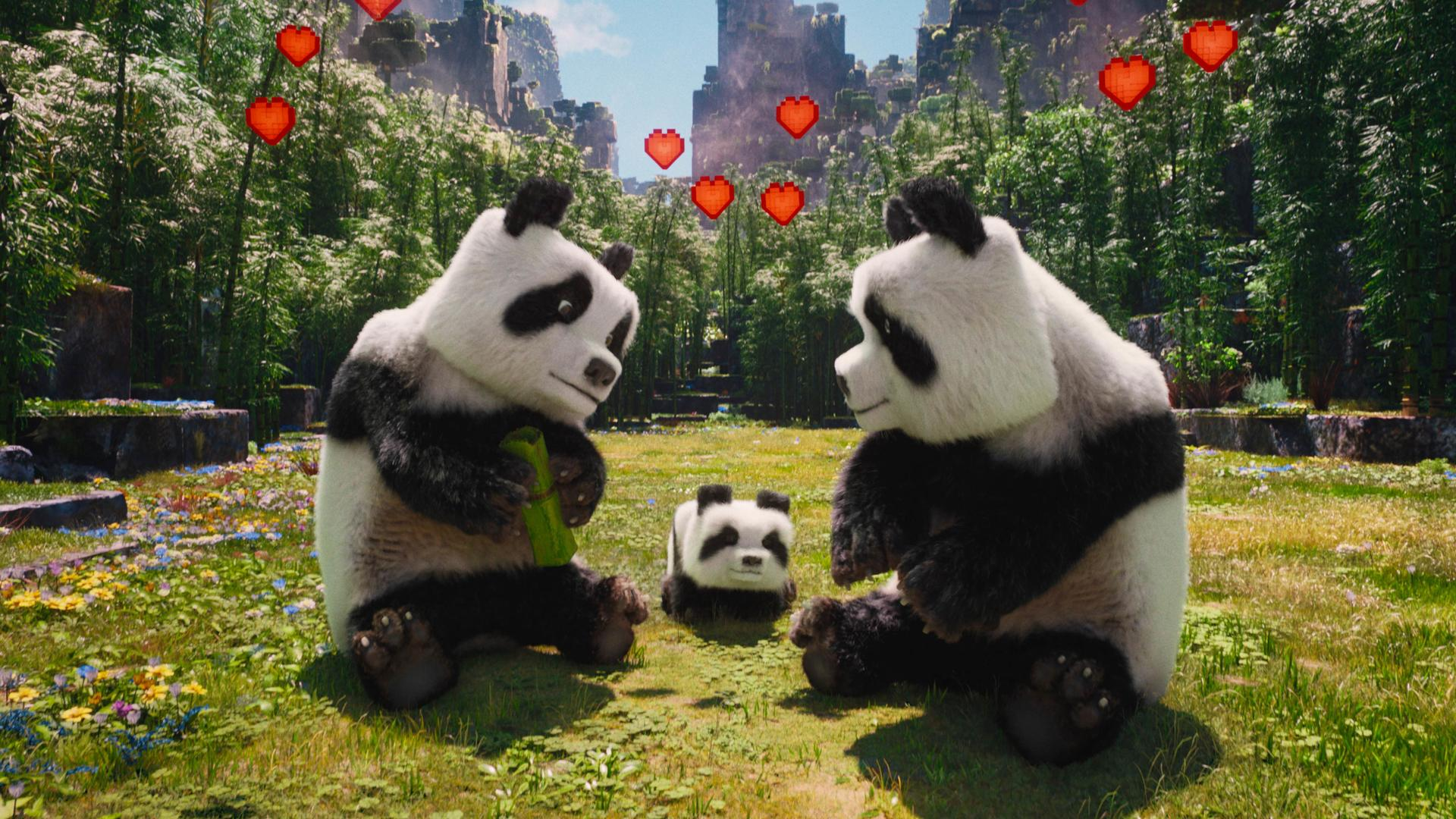 Drei Pandas sitzen im Gras. Einer isst Bambus. Rote Herzen schweben über der Szene.