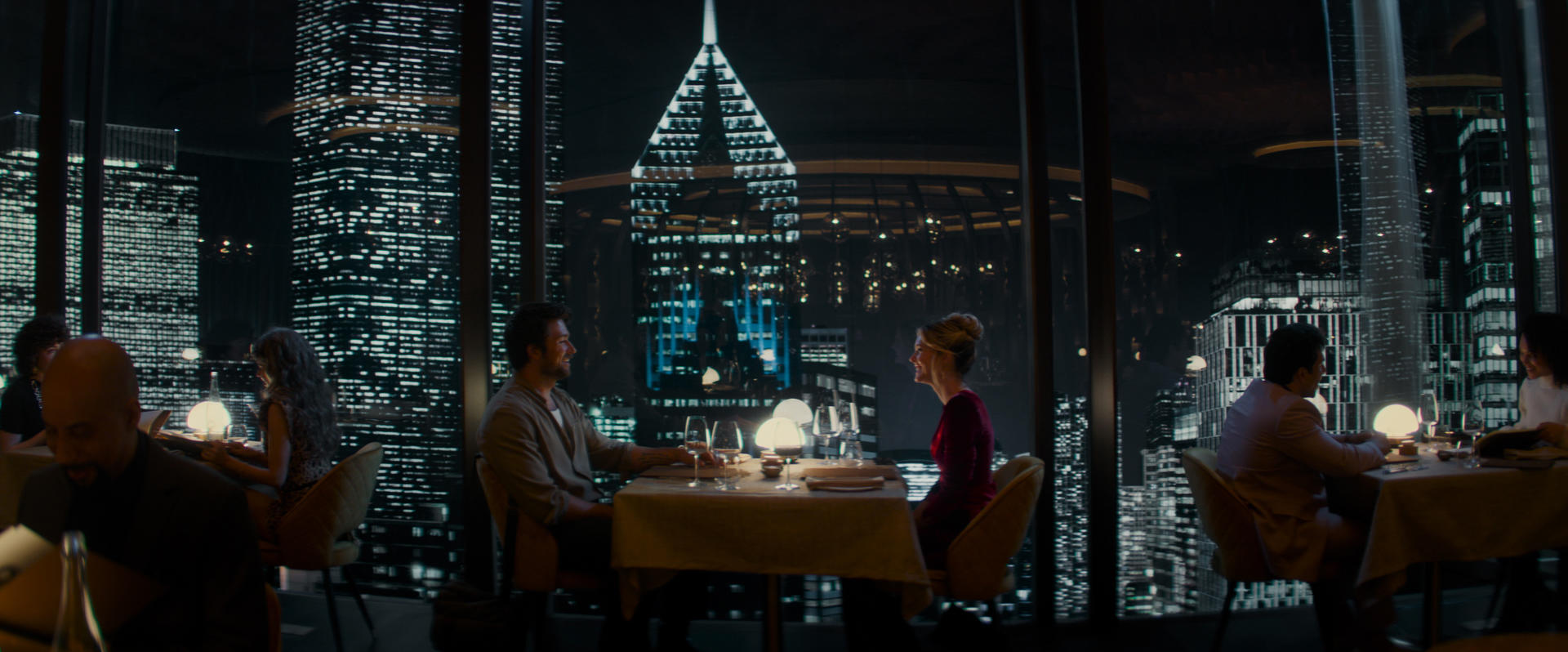 Paar im Restaurant schaut sich an. Stadtlichter sind draußen am Fenster zu sehen.