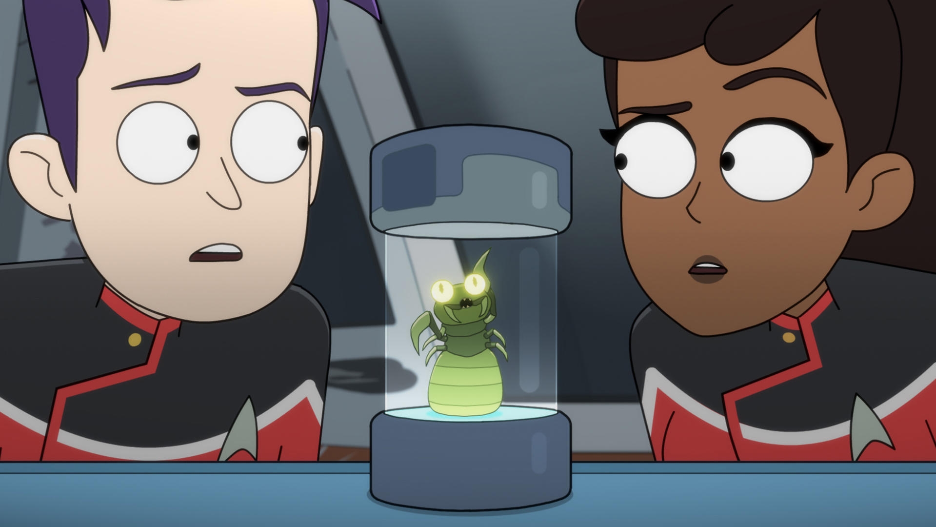 Zwei Star-Trek-Crewmitglieder betrachten einen Alien in einem Behälter. Der Alien ist grün und leuchtet.