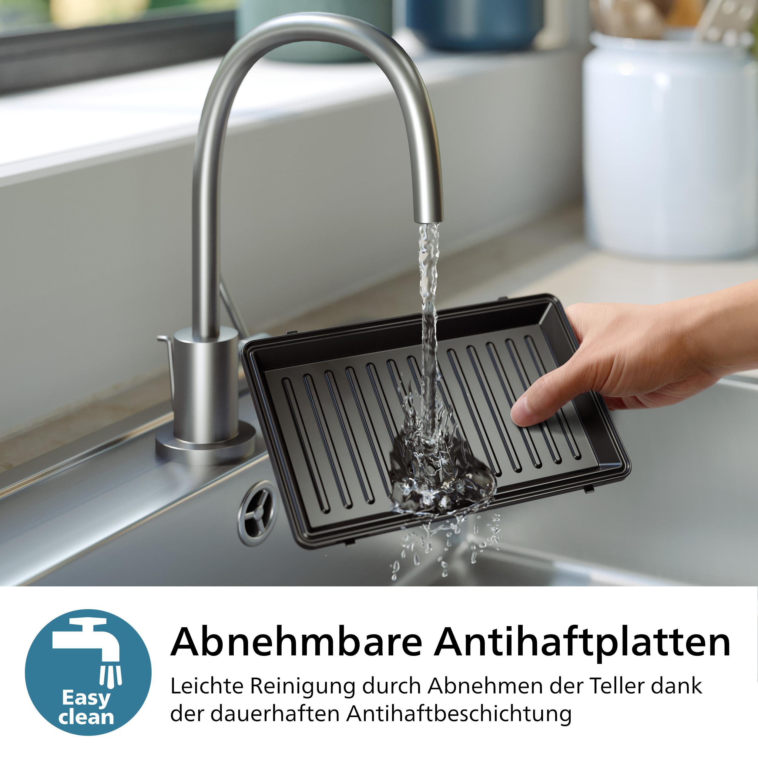 Eine Person spült eine herausnehmbare Platte unter einem Wasserhahn in einem Edelstahlbecken ab.