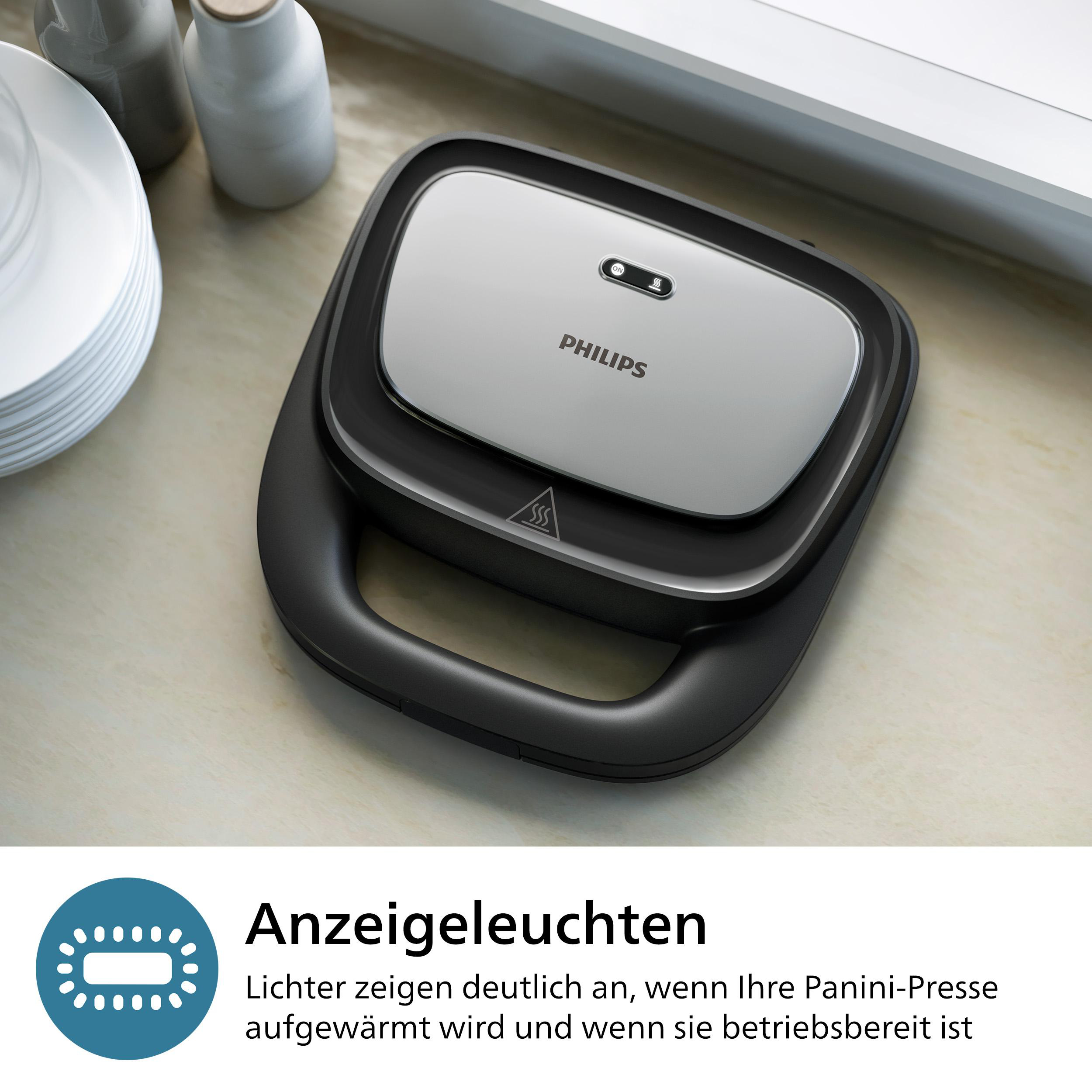 Eine schwarz-silberne Panini-Presse auf einer hellen Oberfläche. Kontrollleuchten sind oben sichtbar.