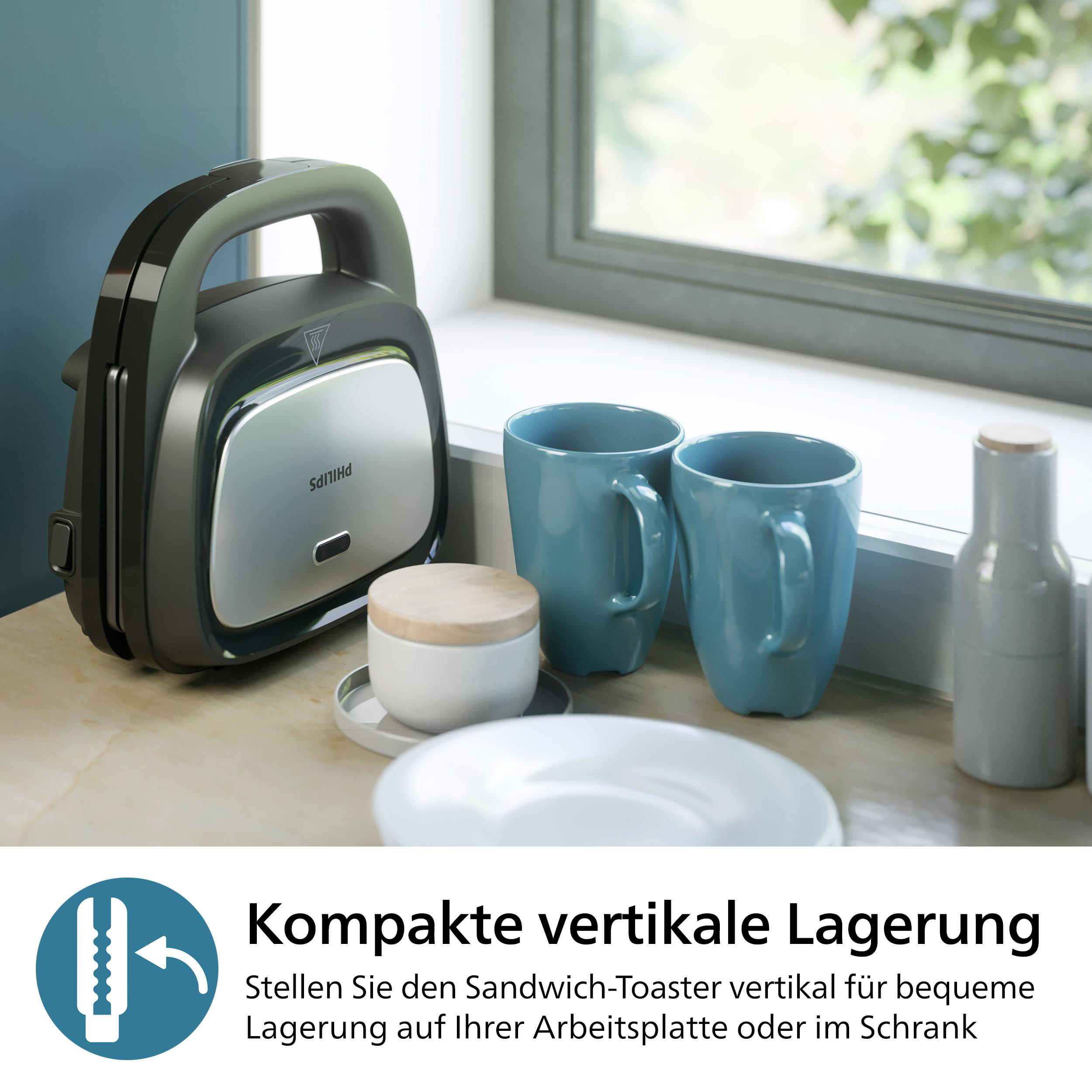 Eine Panini-Presse auf einer Arbeitsplatte. Zwei blaue Becher, ein Teller und ein Glas.