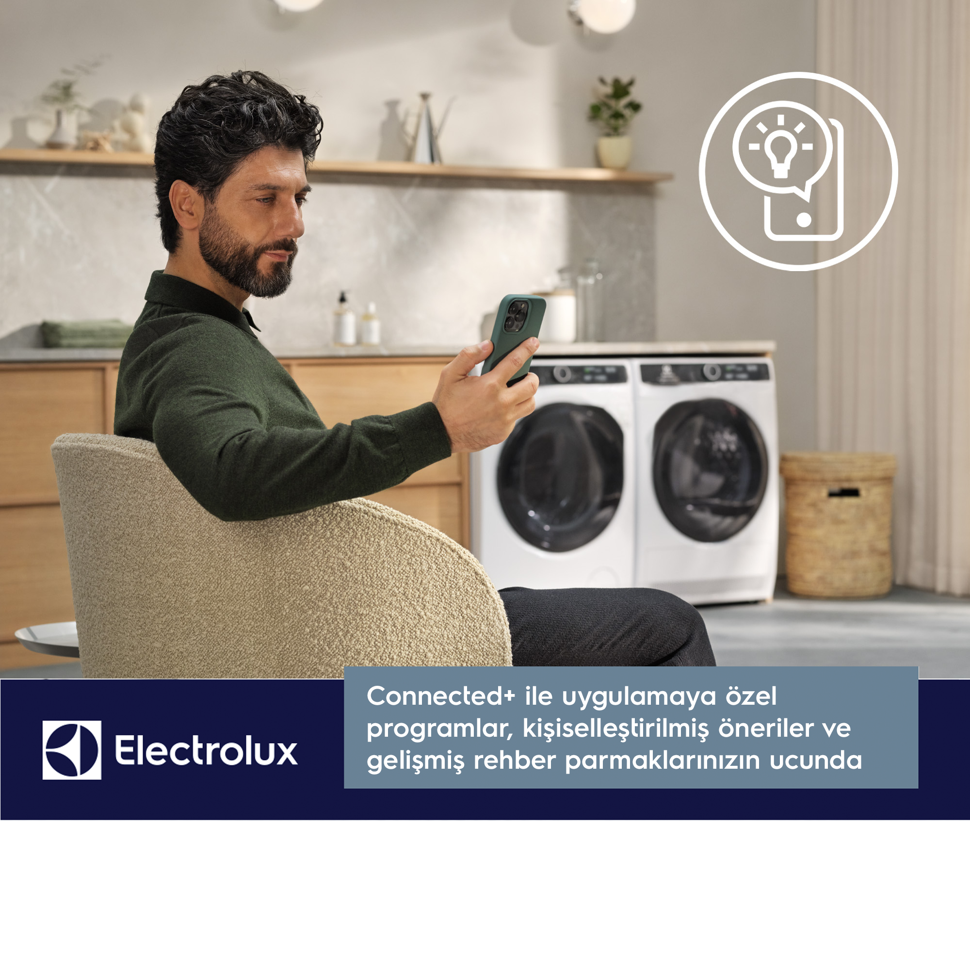 Bir çamaşır makinesinin yanında akıllı telefon kullanan adam.