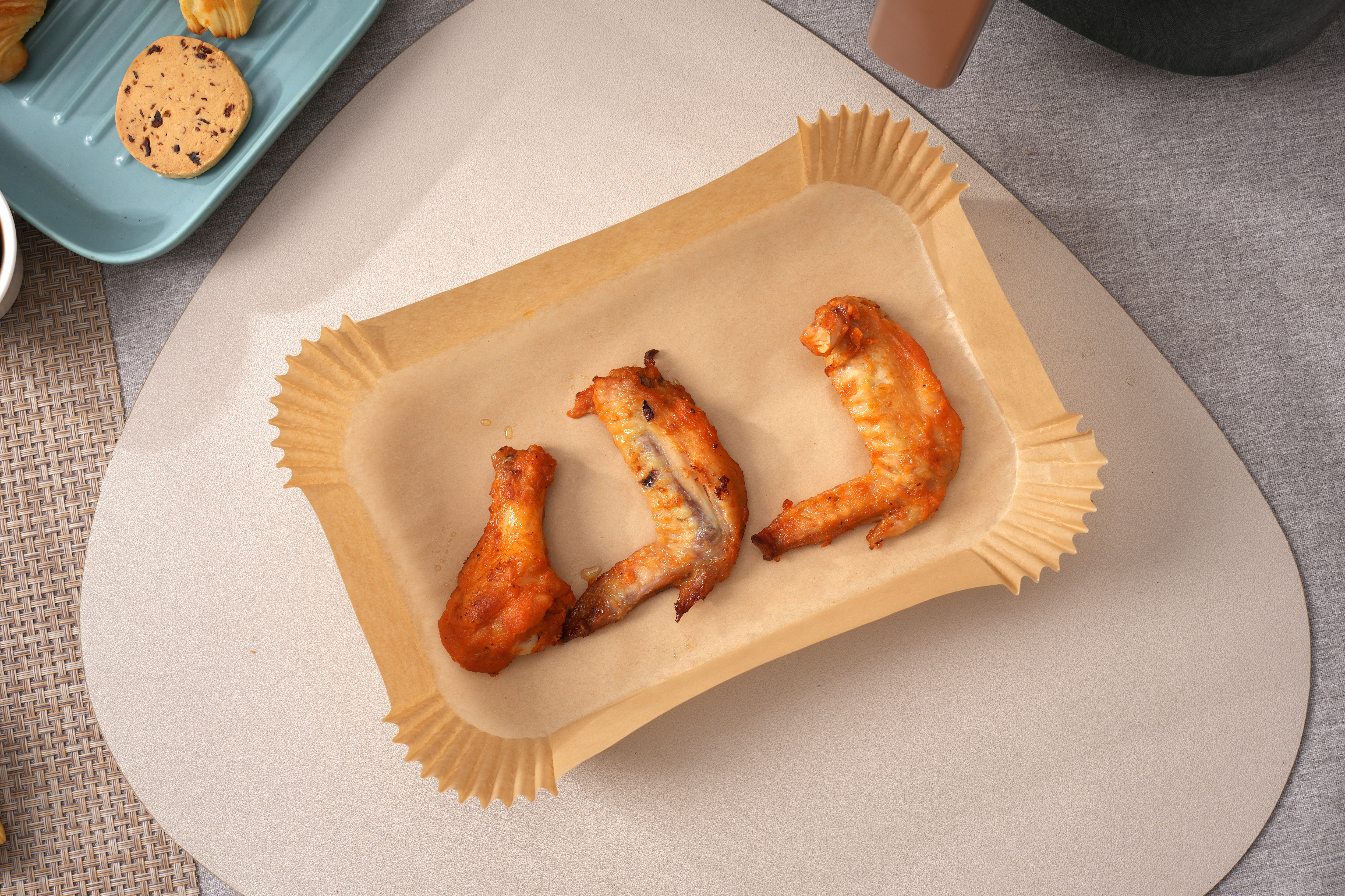 Pusta papierowa tacka do pieczenia na stole z ciastkami i niebieskim talerzem.