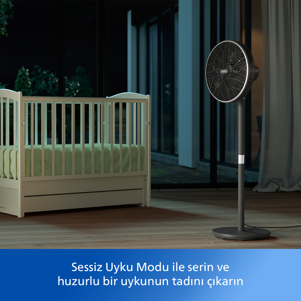 Siyah bir vantilatör, beyaz bir beşik yanında duruyor. Sahne, gece dışarıda.