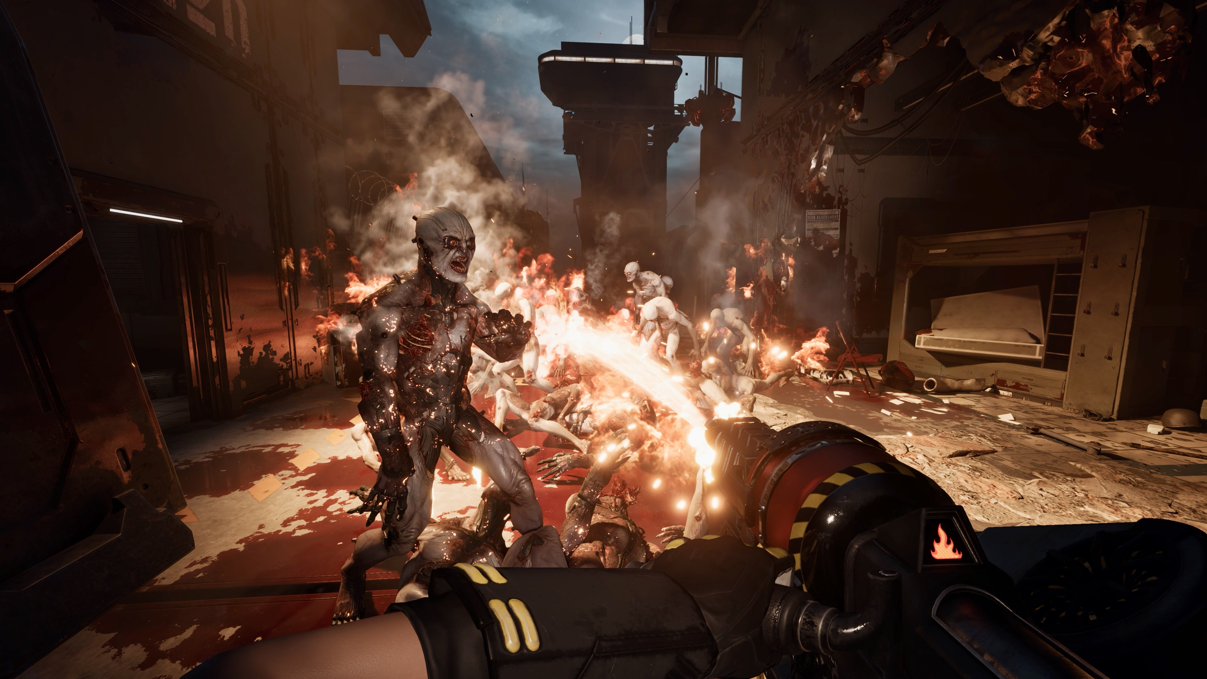 Vue à la première personne tirant sur des zombies avec du feu. La scène se déroule dans une zone industrielle détruite.