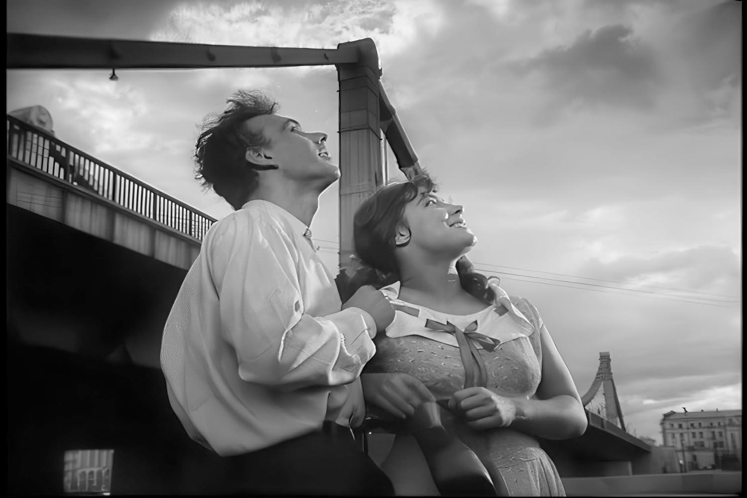 Paar blickt nach oben, unter einer Brücke, in einem Schwarzweiß-Filmstill.