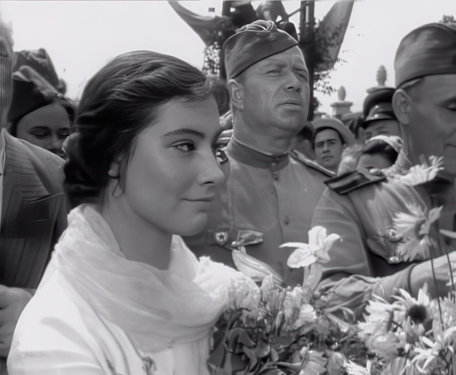 Frau betrachtet Blumen, Soldaten im Hintergrund, in einem Filmstill.