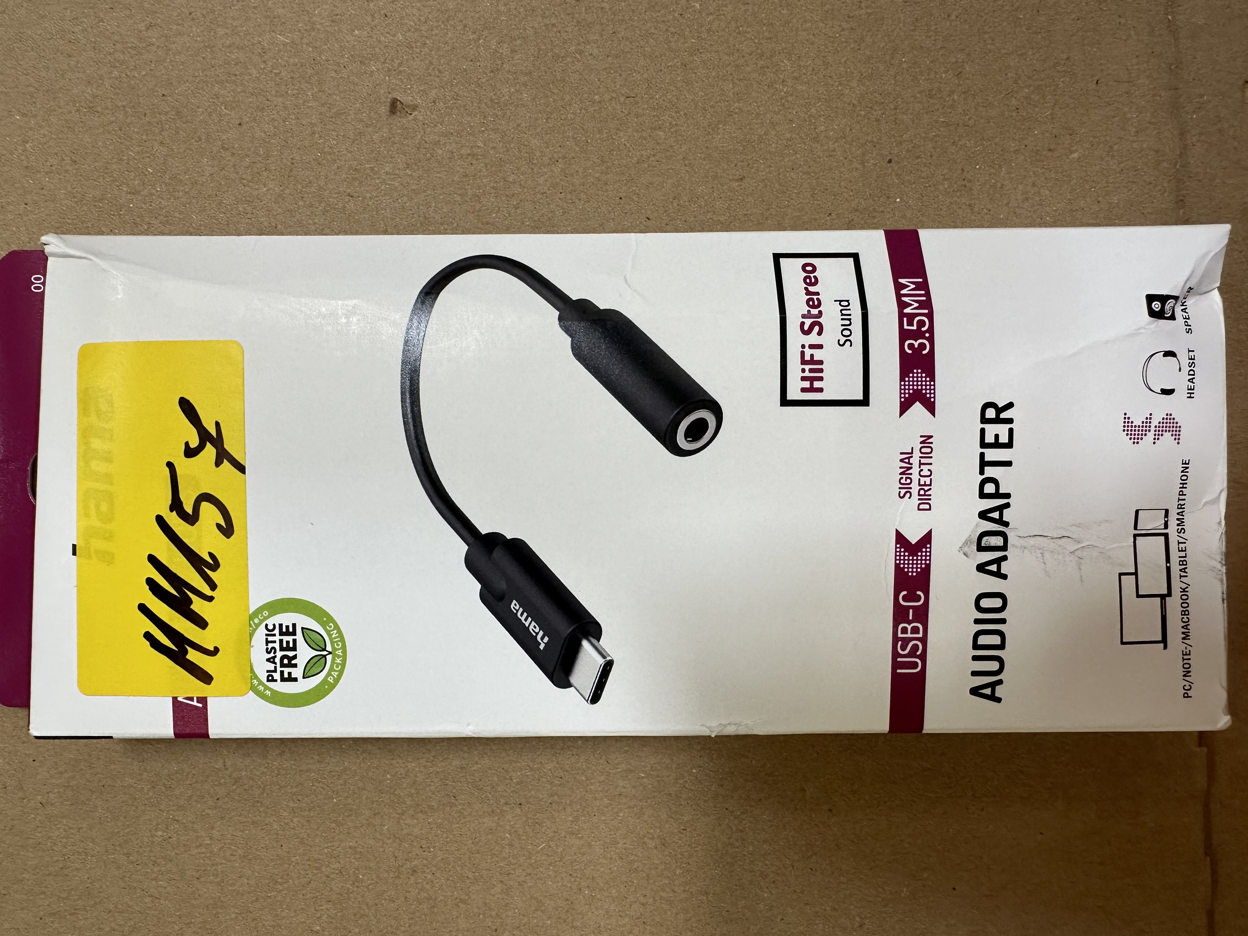 Pakowany adapter audio USB-C do 3,5 mm. Czarny adapter, białe pudełko z tekstem i obrazami.