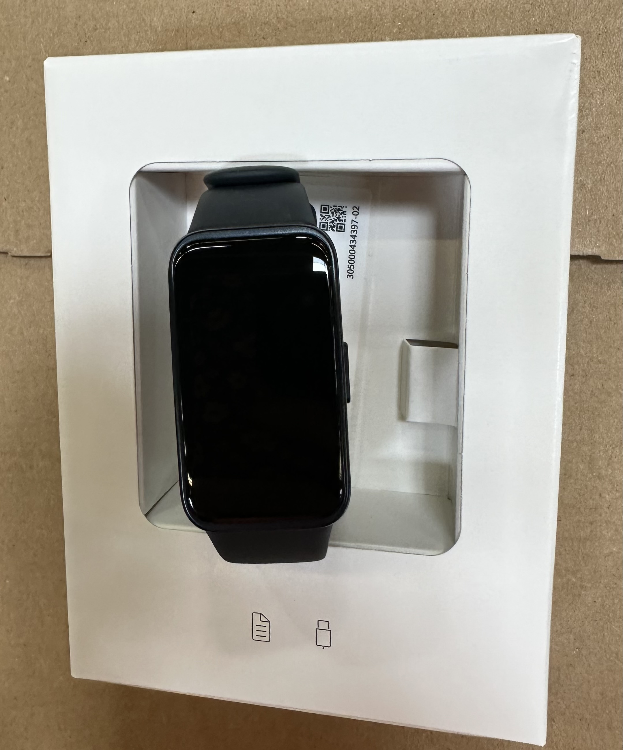 Czarny smartwatch Huawei w białym pudełku. Zegarek jest wyświetlany z czarnym ekranem. Pudełko ma kod QR.