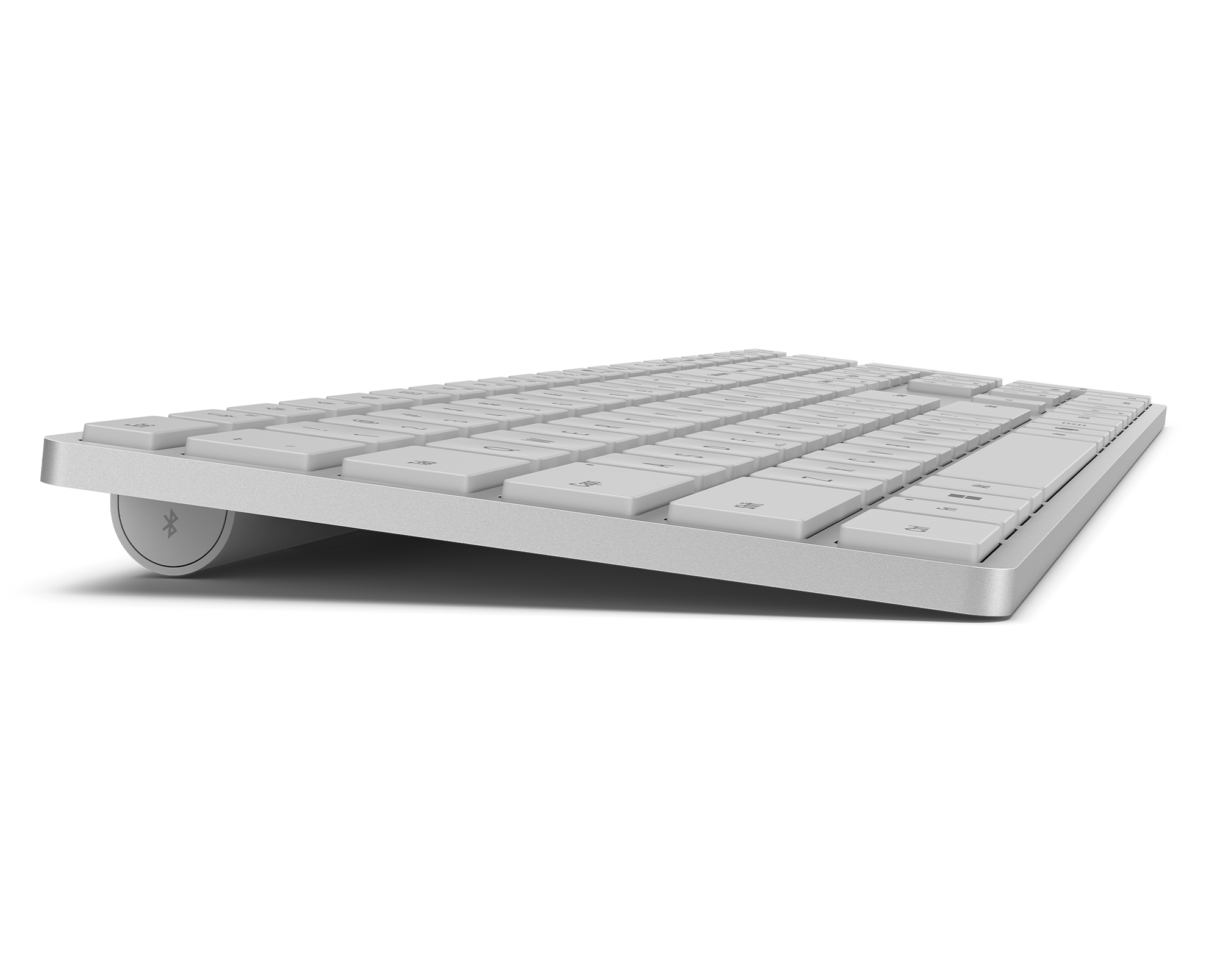 Silberne kabellose Tastatur mit weißen Tasten, leicht angewinkelt. Bluetooth-Logo sichtbar. Isoliert auf Weiß.