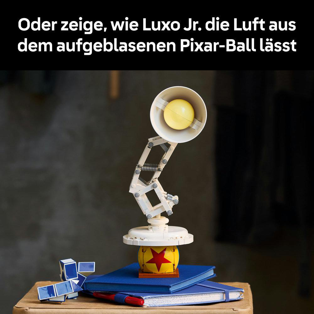 Luxo Jr. Lampe mit Pixar-Ball und Notizbüchern. Die Lampe ist weiß mit gelber Birne. Der Ball entleert sich.