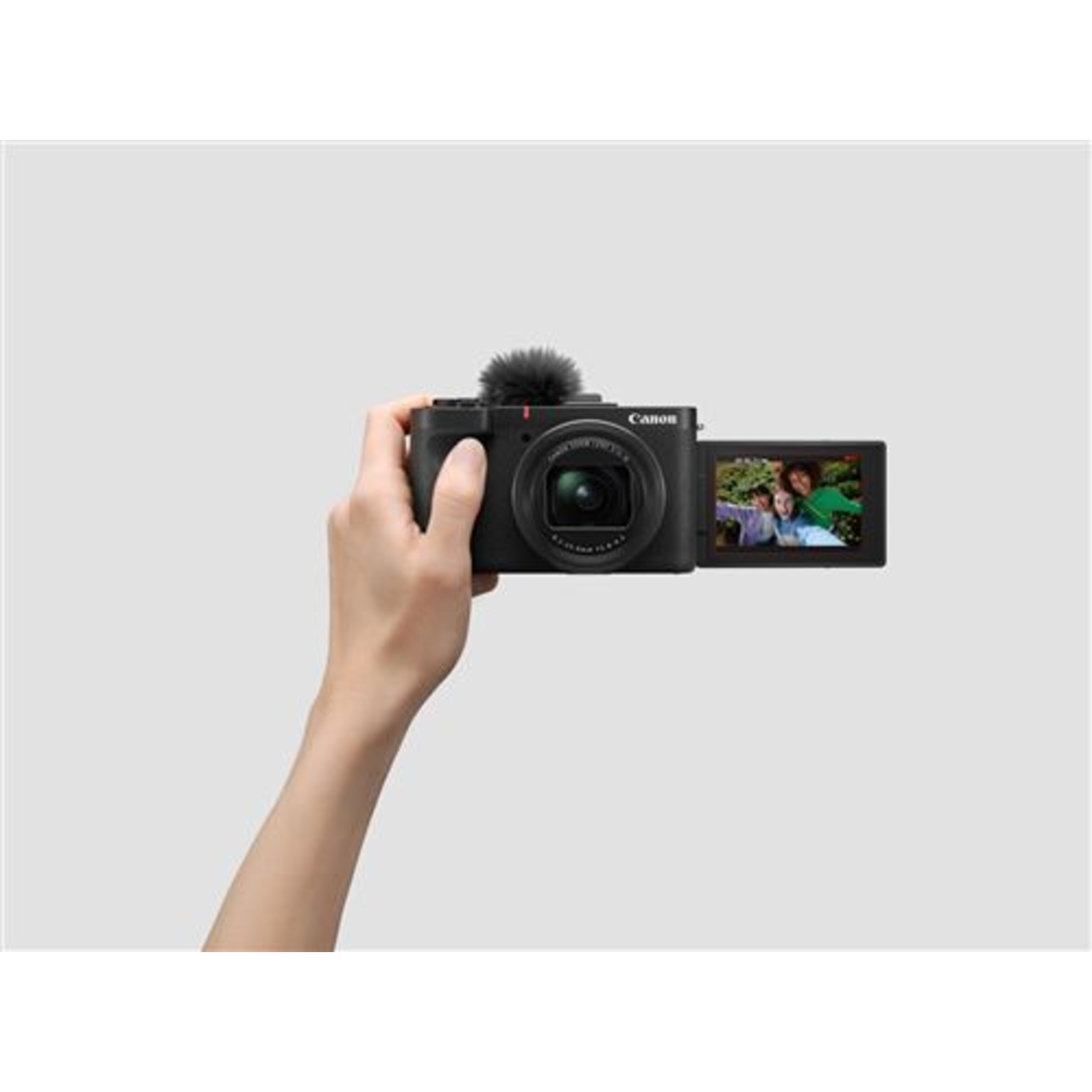 Hand holding a Canon camera showing a video. Two people are visible on screen.