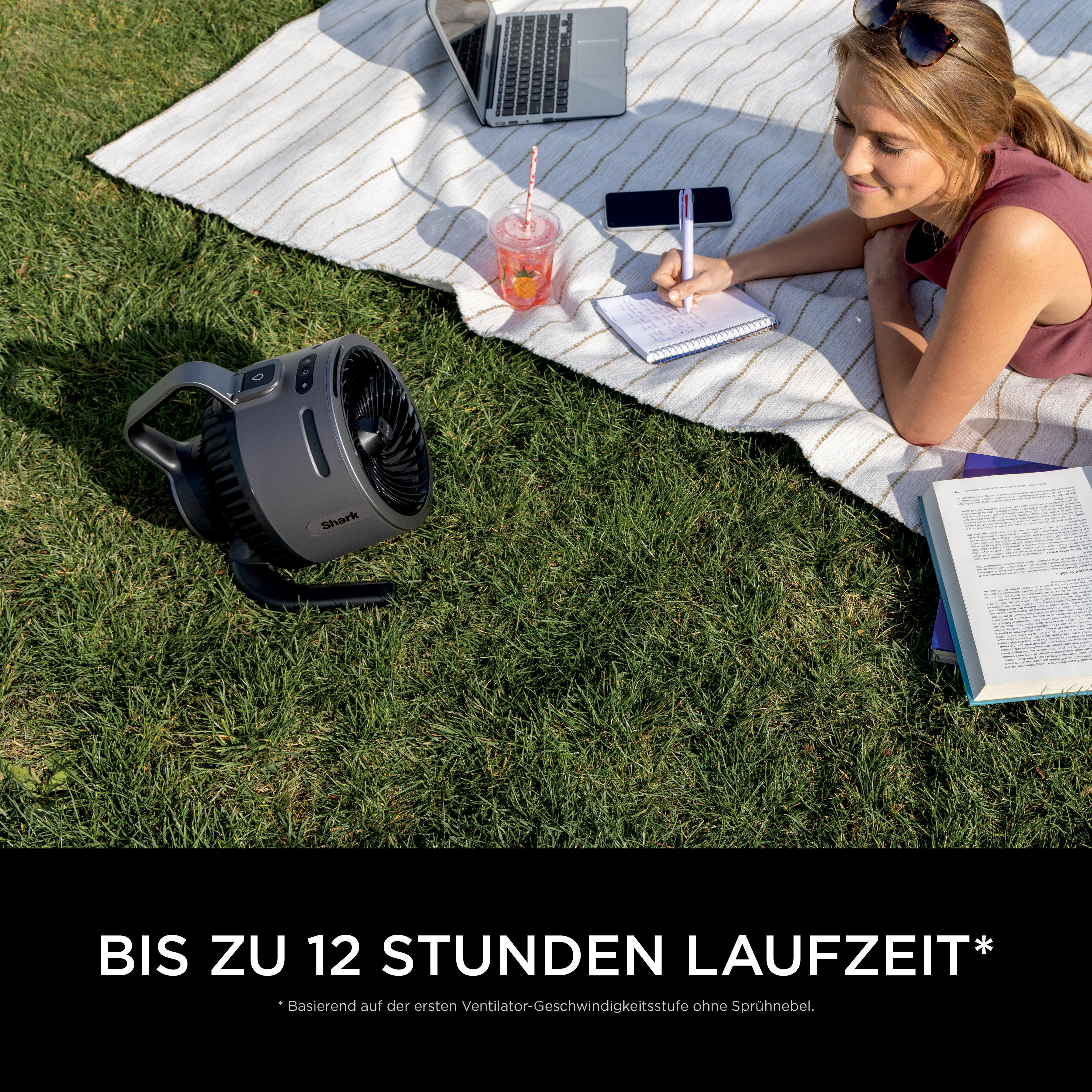 Frau schreibt in Notizbuch mit Ventilator auf Decke im Gras.