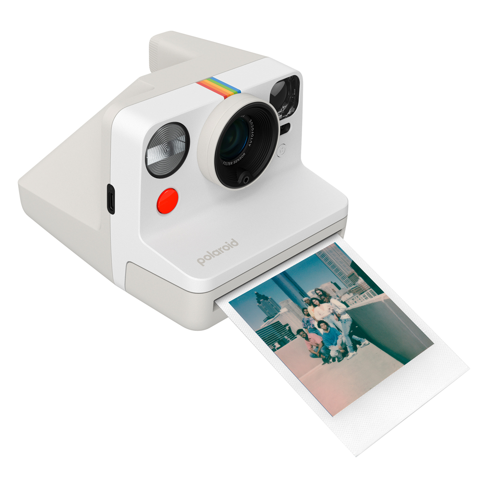 Bir çatıdaki insanların fotoğrafını çıkaran beyaz bir Polaroid kamera.