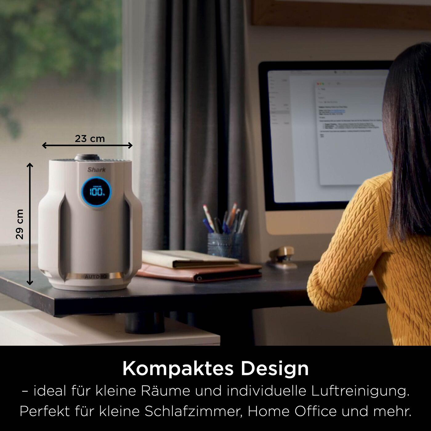 Luftreiniger auf dem Schreibtisch, Abmessungen gezeigt. 29 cm hoch, 23 cm breit. Büro mit Computer im Hintergrund.