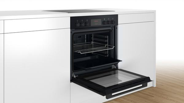 Ein Bosch-Ofen mit offener Tür, eingebaut in einen weißen Küchenschrank.