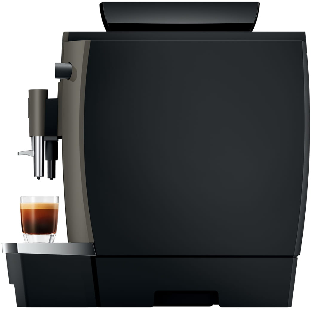 Vista laterale di una macchina da caffè scura con un bicchiere di caffè. Base nera e sfondo neutro.