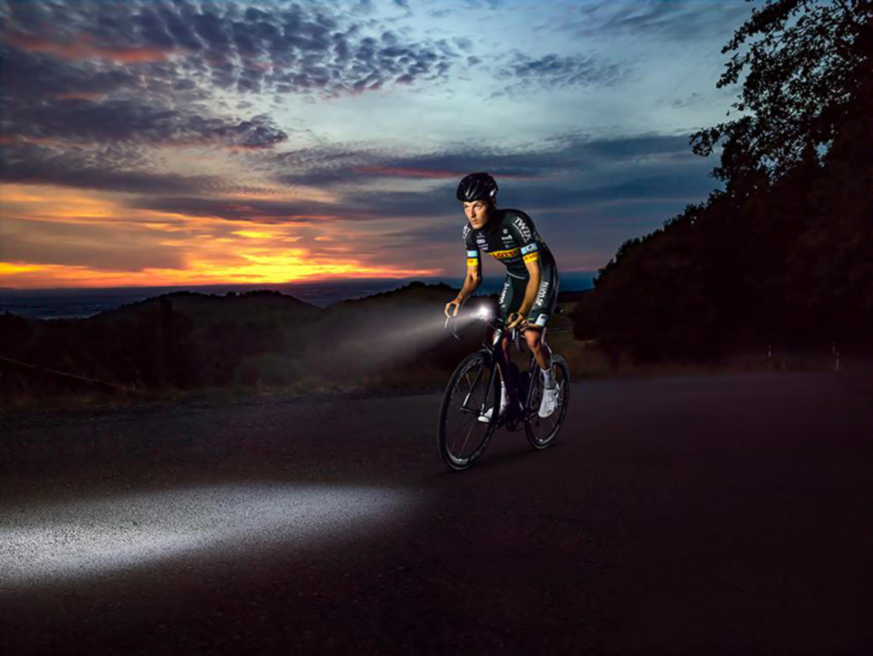 Radfahrer mit Fahrradlichtern auf Straße bei Sonnenuntergang.