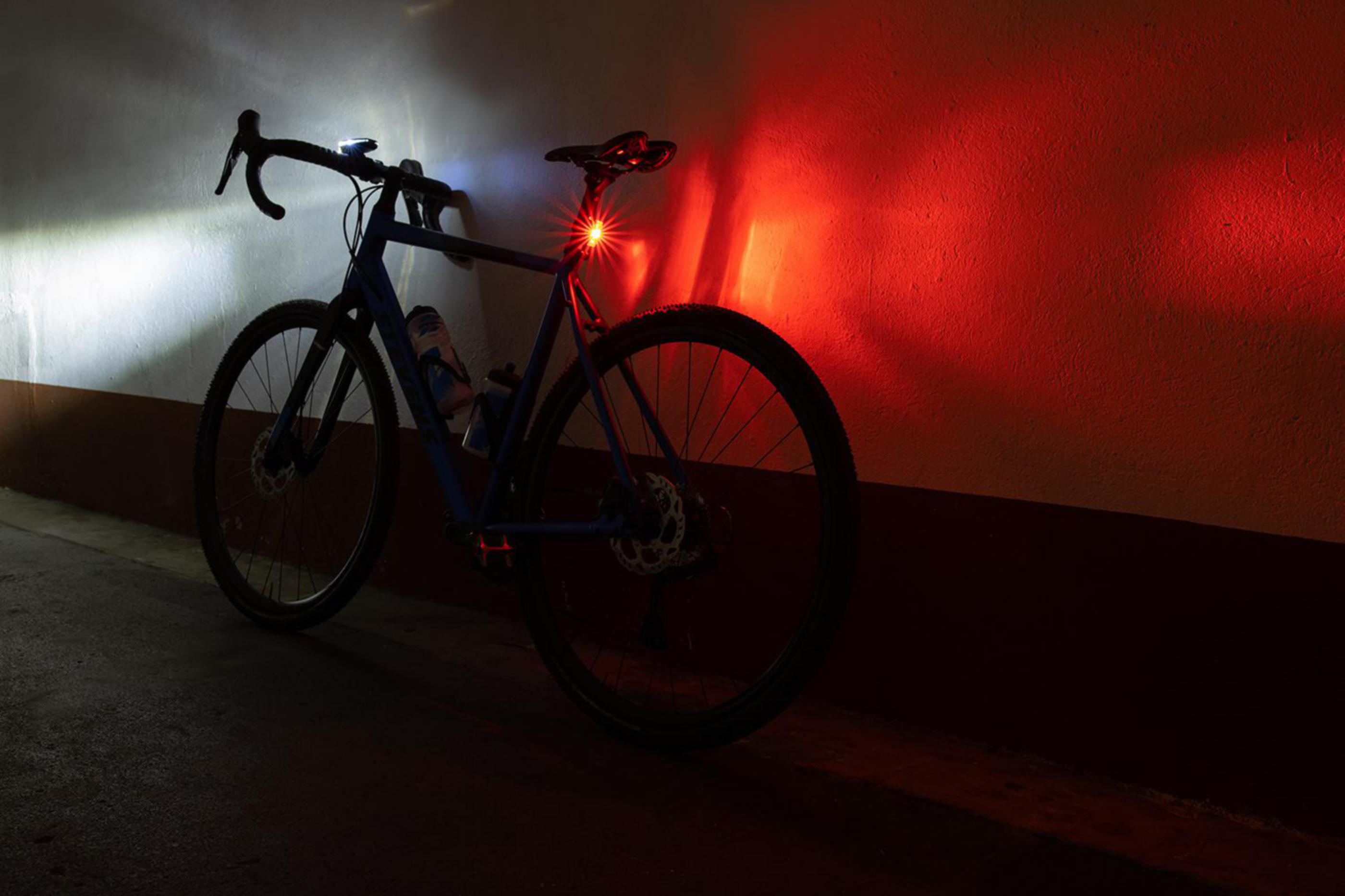 Fahrrad mit Lichtern in einem Tunnel. Das vordere Licht ist weiß, das hintere rot.