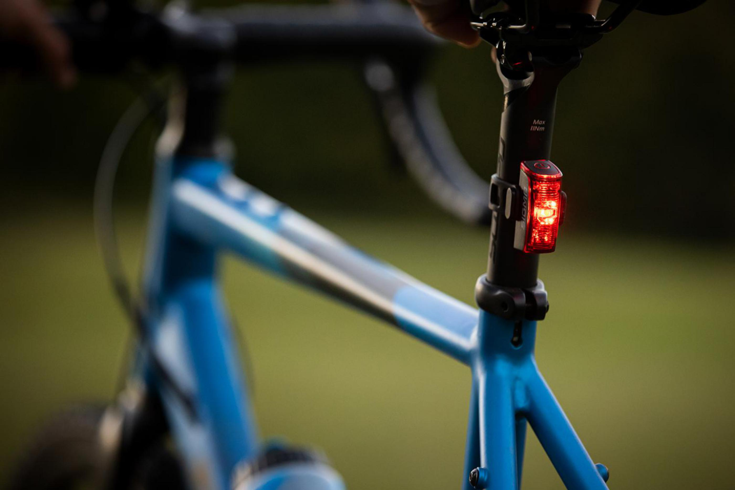 Nahaufnahme eines Fahrradsattels mit rotem Rücklicht. Blauer Fahrradrahmen.