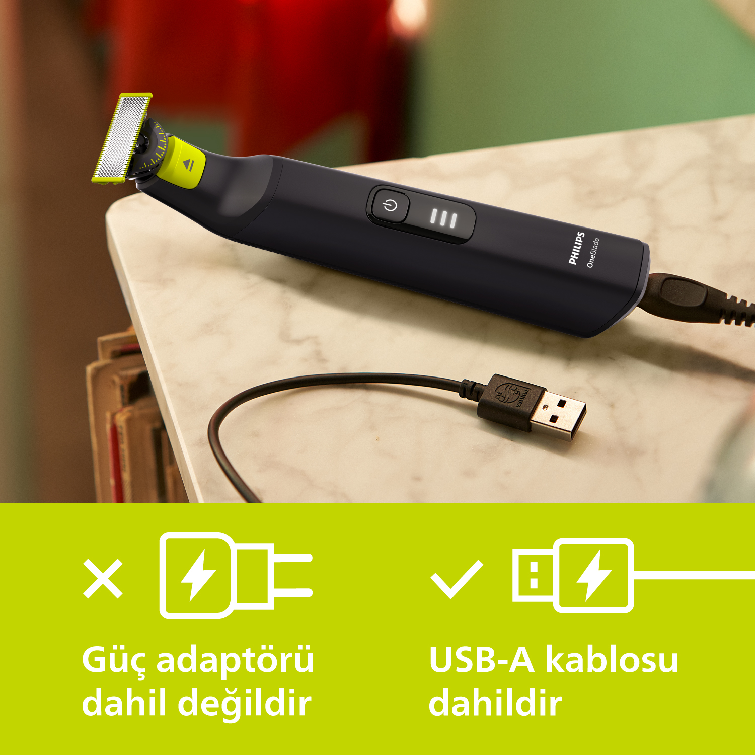 Siyah elektrikli tıraş makinesi ve şarj kablosu masada.
