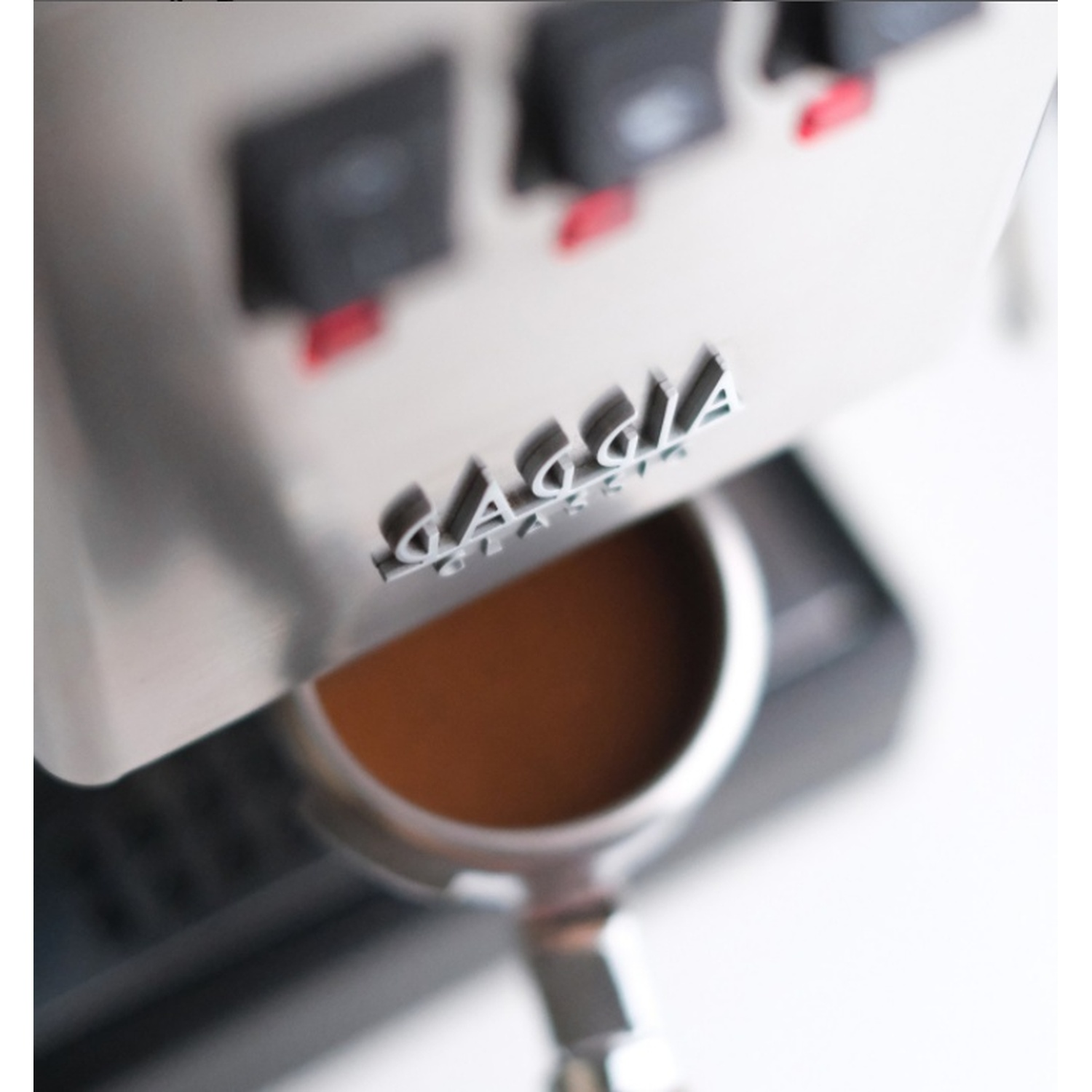 Primo piano del portafiltro di una macchina da caffè, con caffè che si versa in una tazza. Logo Gaggia Classic.