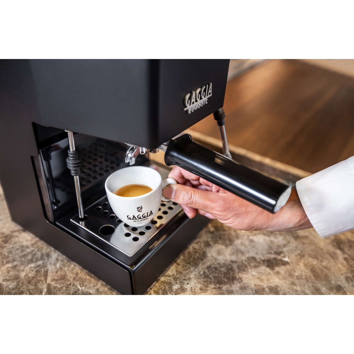 Un barista versa l'espresso in una tazza bianca, macchina del caffè sullo sfondo.